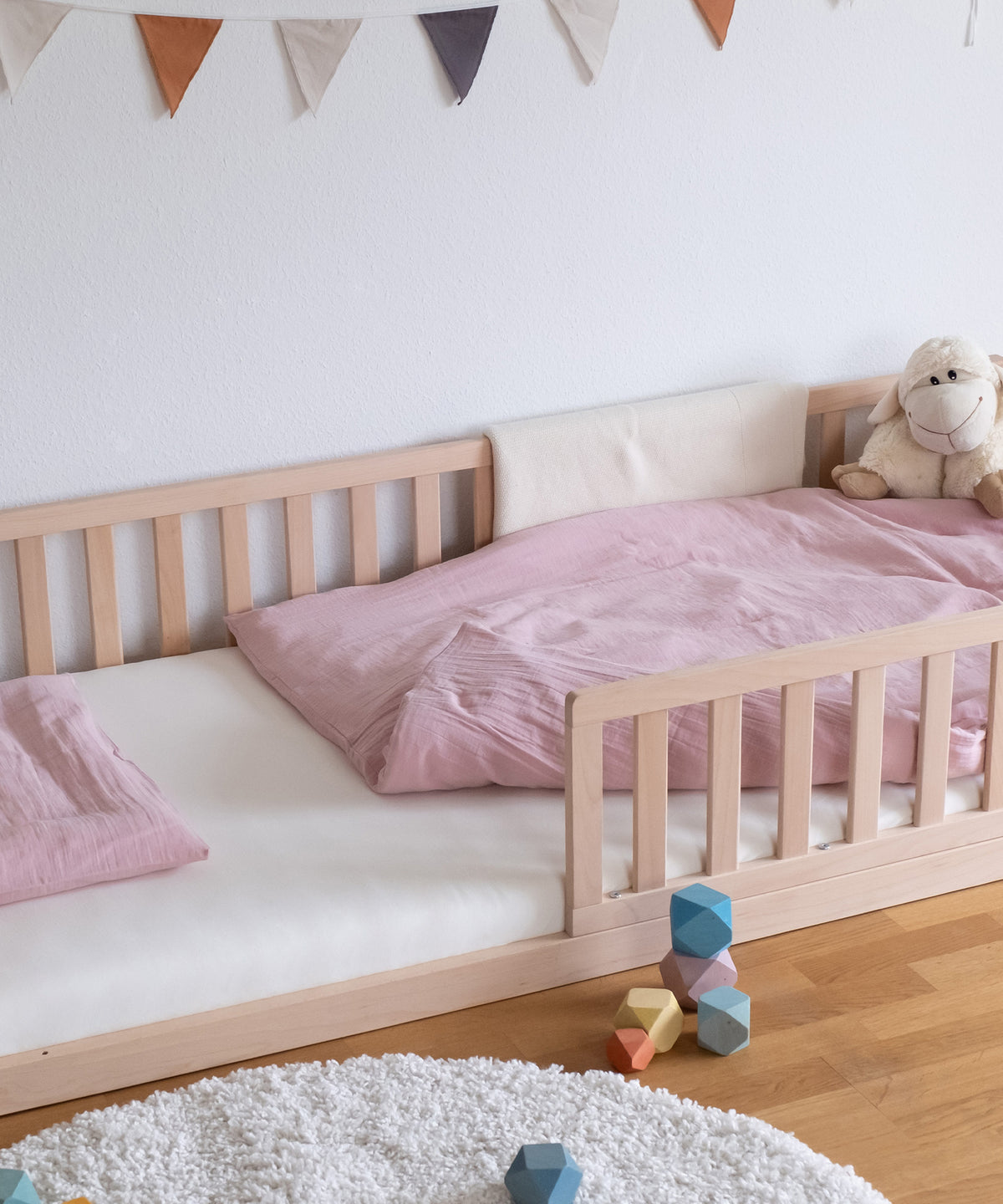 Bodenbett mit Spannbettlaken und Musselin-Bettwäsche rosa.