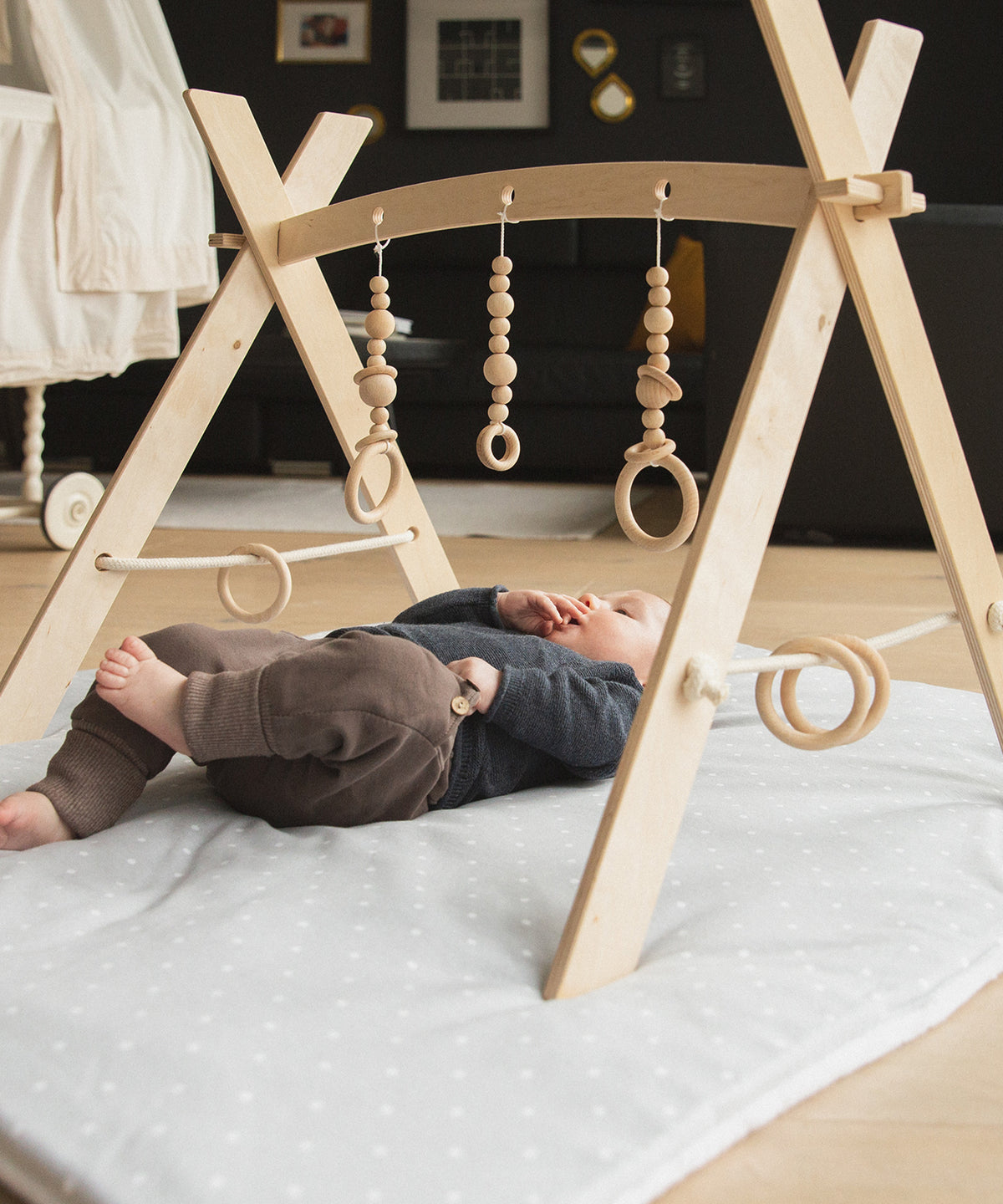 Baby liegt auf Decke unter dem Spielbogen.