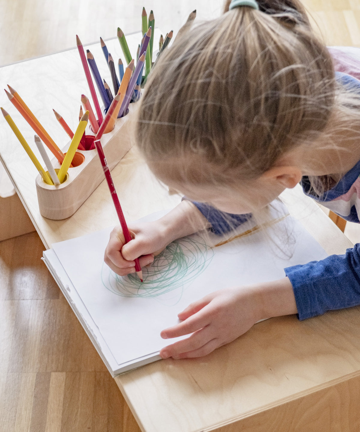 Kind malt ein Bild, daneben steht Stiftehalter.