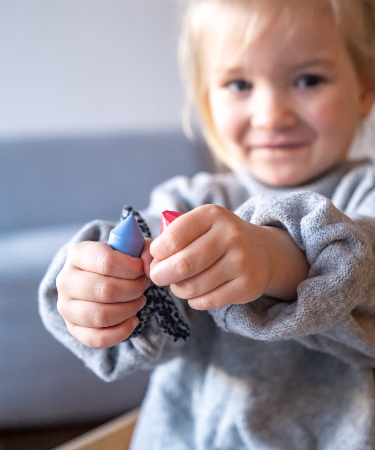 Mädchen hält in jeder Hand einen Wachsmalstift.