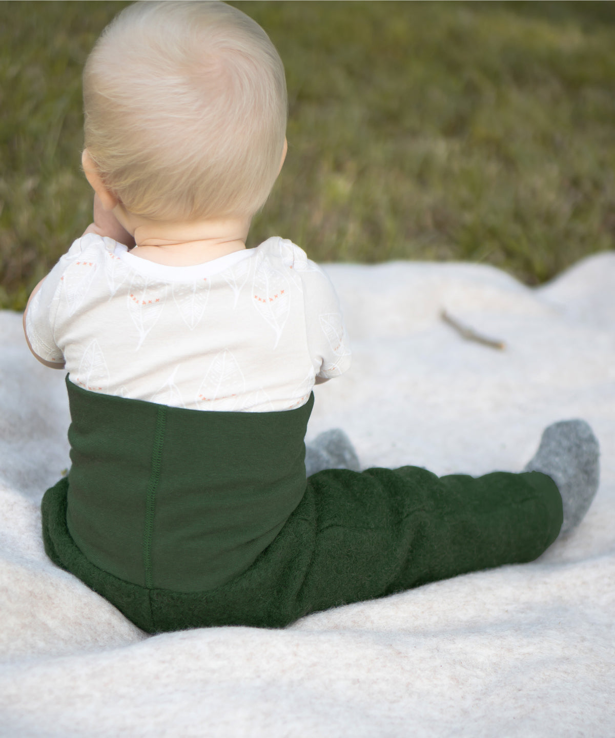 Baby sitzt auf einer Walkdecke. 