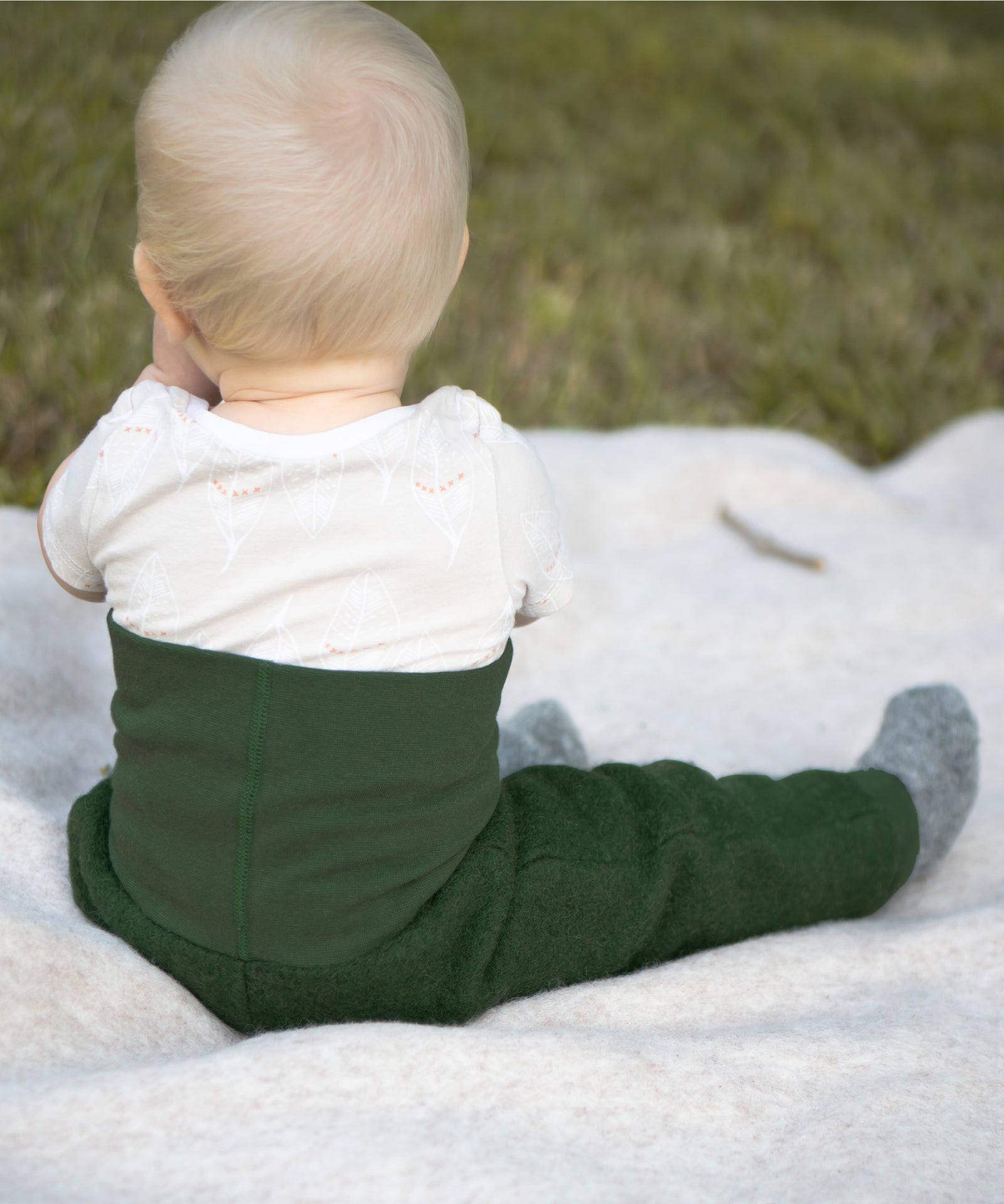 Kuschelig & warm*Die Walkhose aus Schurwolle ist wärmeregulierend und kuschelig weich. Der hohe Bund sorgt für einen perfekten Sitz beim Krabbeln.|Baby sitzt auf einer Walkdecke. 