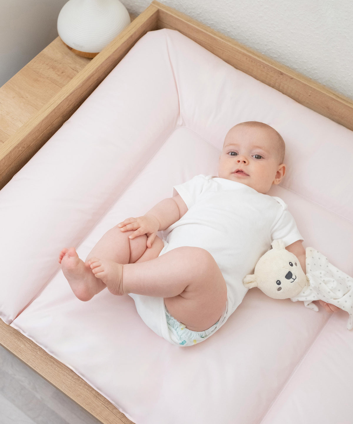 Baby liegt auf Wickelauflage abwaschbar 72x85 cm im Rosé.