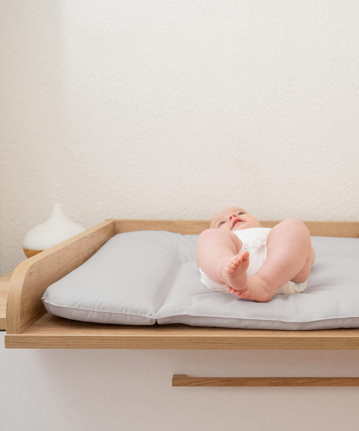 Baby auf hellgrauer Wickelauflage abwaschbar.