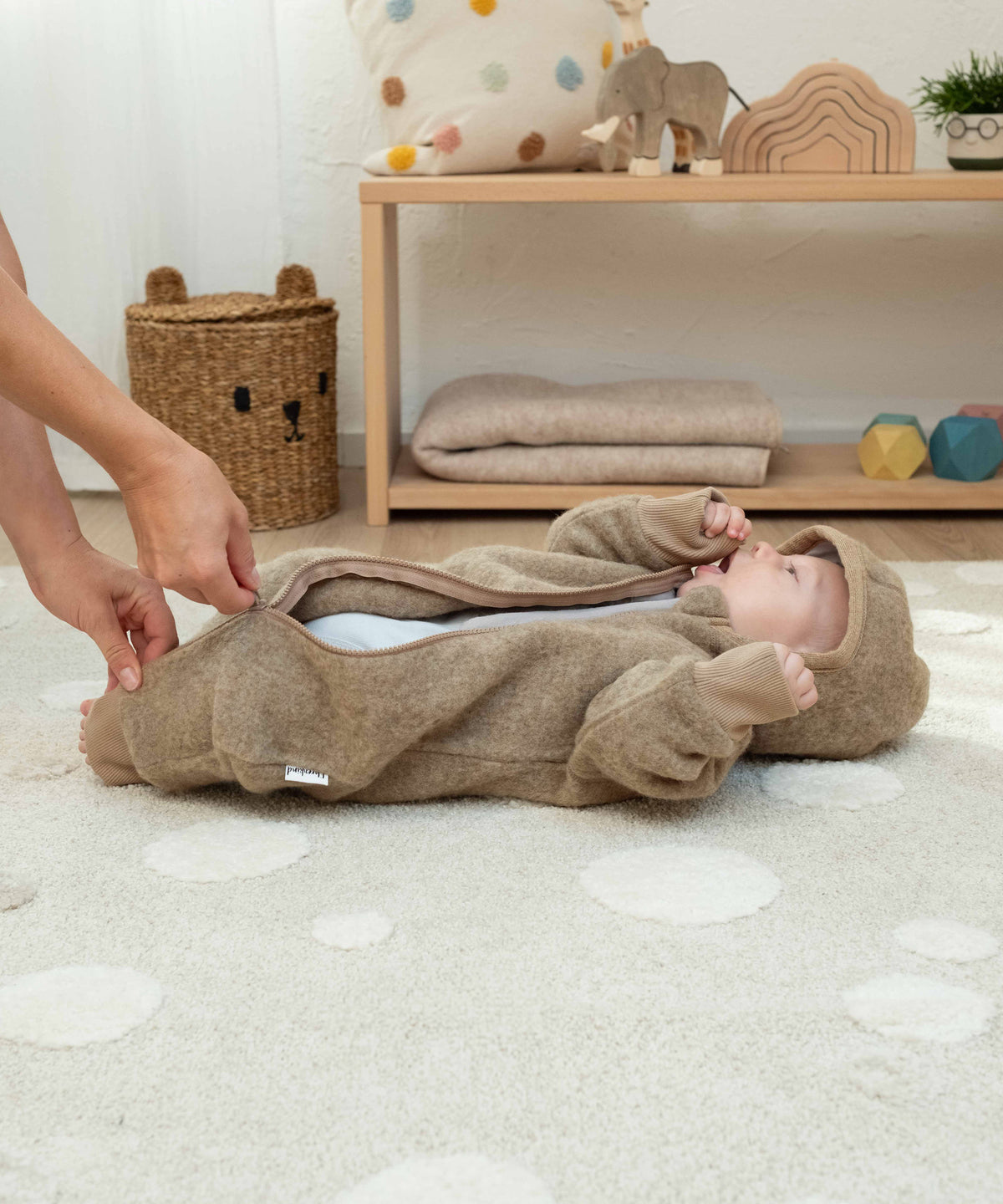 Mutter zieht Baby Wollfleeceoverall an.
