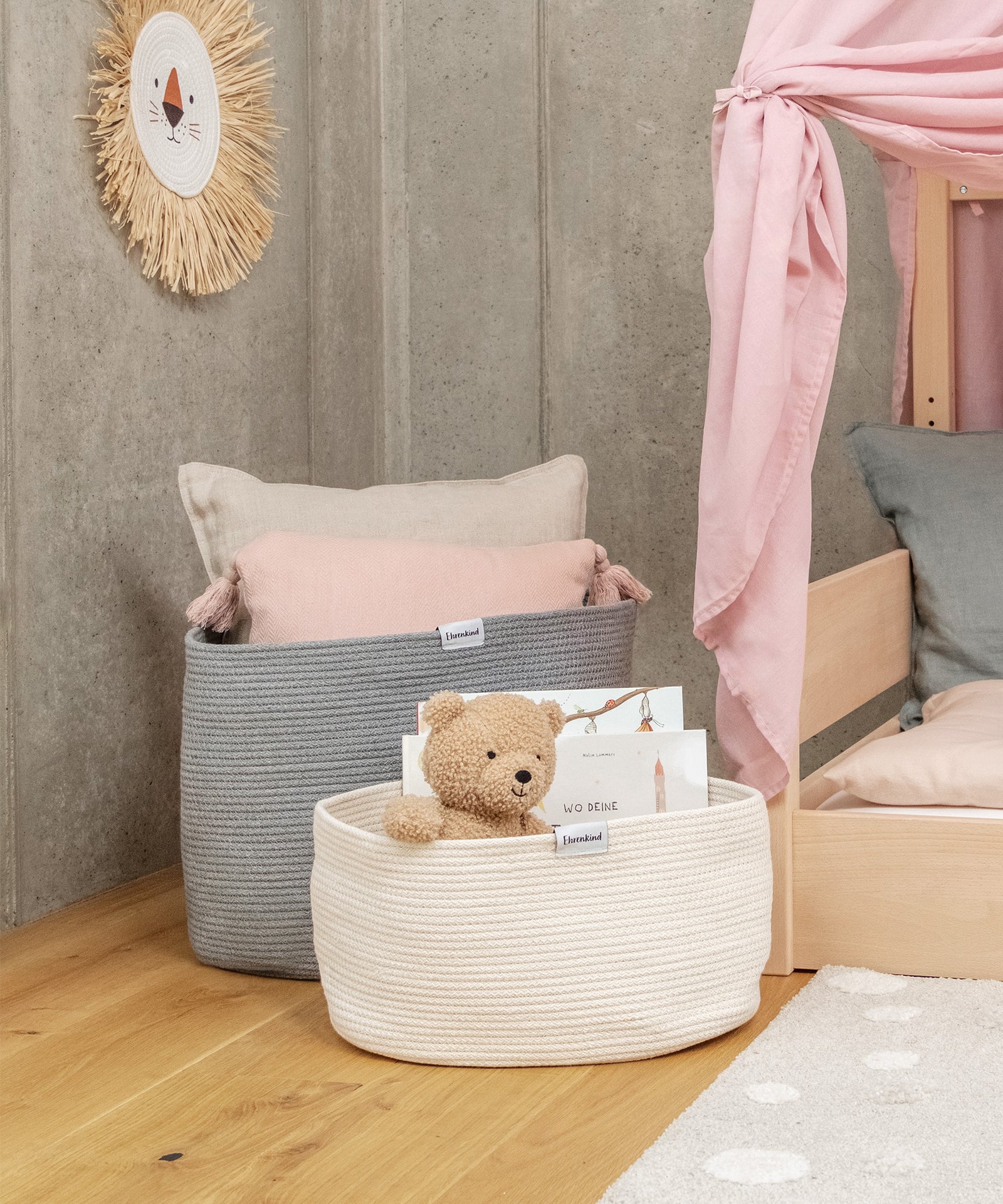 Aufbewahrungskörbe mit Kissen und Teddy am Bett.