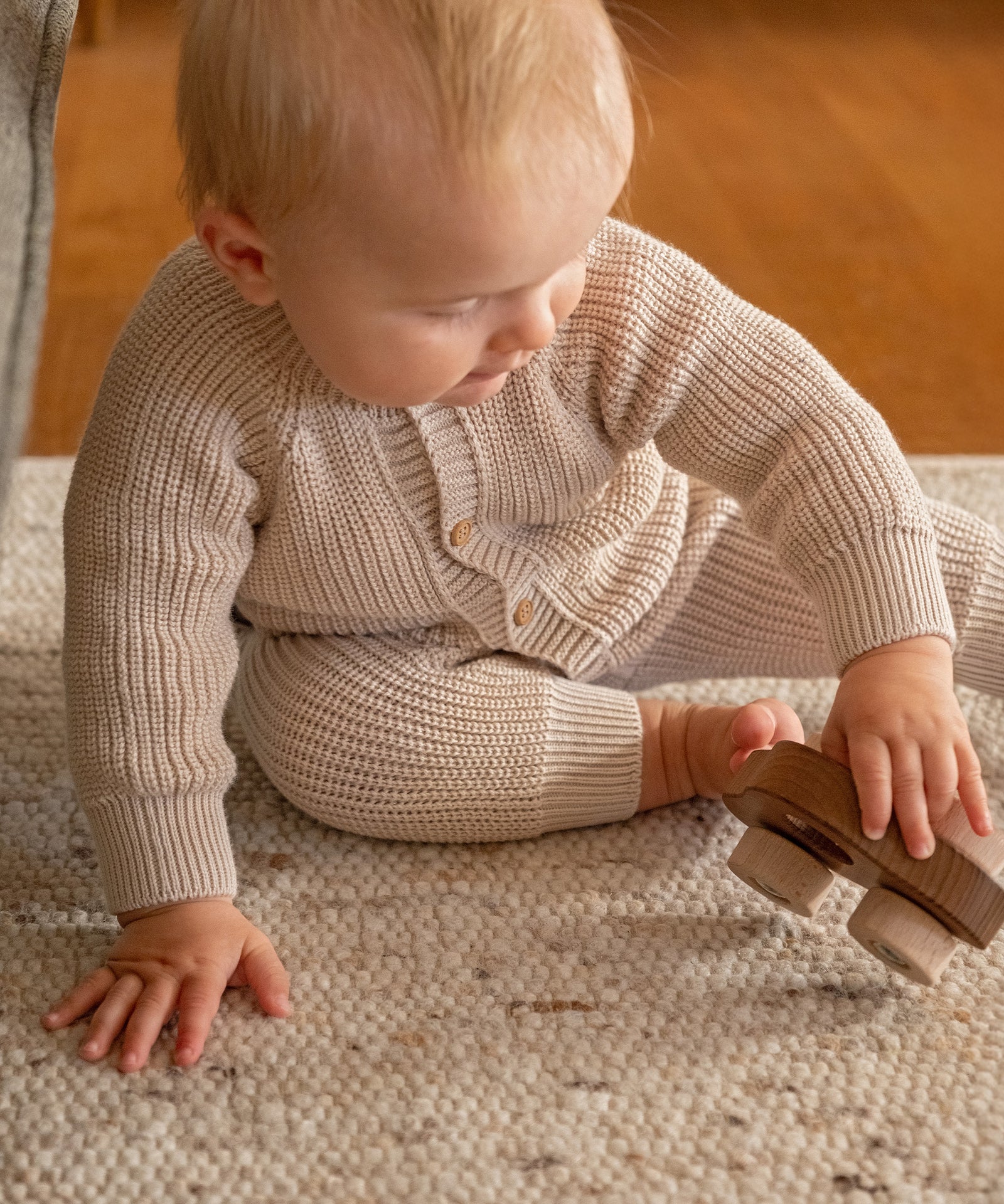 Bequemer Sitz*Rippbündchen an Armen und Beinen sorgen für guten Halt, ohne einzuengen - perfekt zum Spielen, Schlafen und für unterwegs.|Baby spielt im Strickoverall aus Bio-Baumwolle.