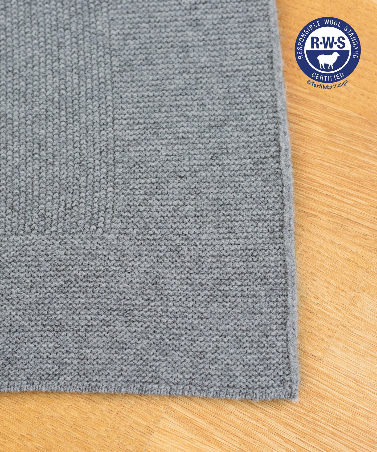 Bio-Lammwolldecke*Unsere Lammwolldecke ist aus 100 % mulesingfreier Schurwolle. Sie stammt aus kontrollierter Tierhaltung mit RWS-Zertifizierung.|Gestrickte Lammwolldecke in Grau.