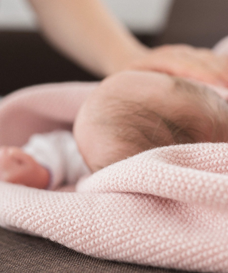 Made in Germany*Die Babydecke aus hochwertiger Bio-Lammwolle wird in Deutschland produziert.|Neugeborenes in rosa Lammwolldecke.