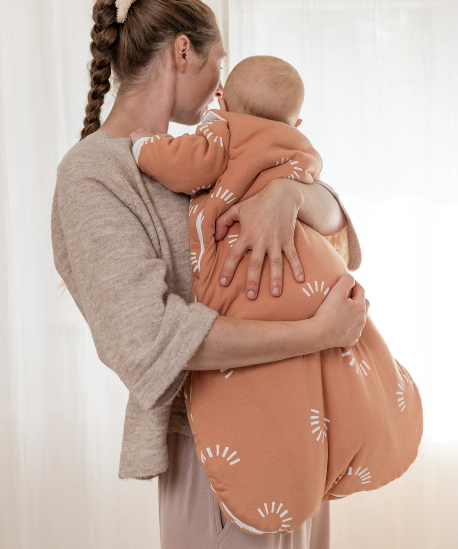 Hautfreundlich & fair produziert*Der Schlafsack mit Bio-Baumwolle wird in Europa hergestellt. Er ist OEKO-TEX® zertifiziert und in liebevollen Designs erhältlich.| Baby trägt den Winter-Schlafsack in Zimt Gemustert.