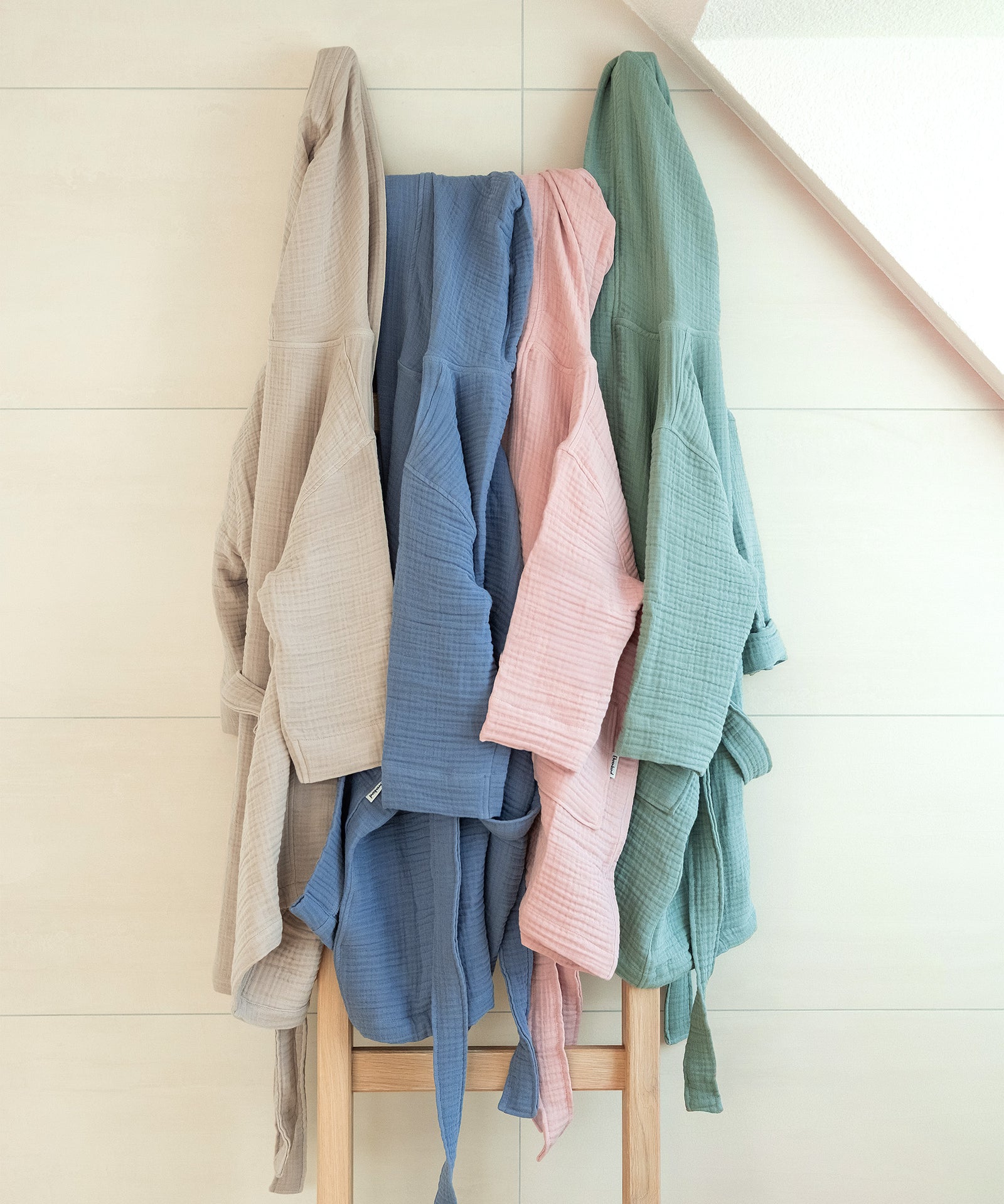 Bademantel Musselin in vier Farben nebeneinander aufgehängt.