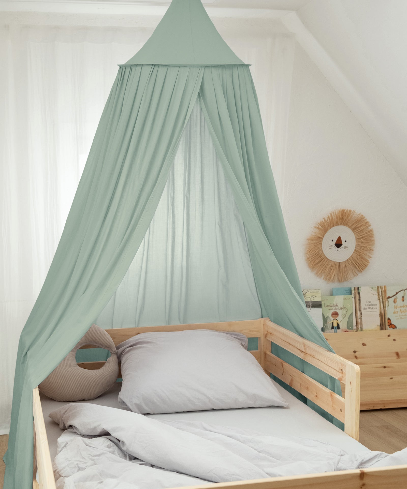 Grüner Baldachin als Betthimmel über einem Kinderbett.