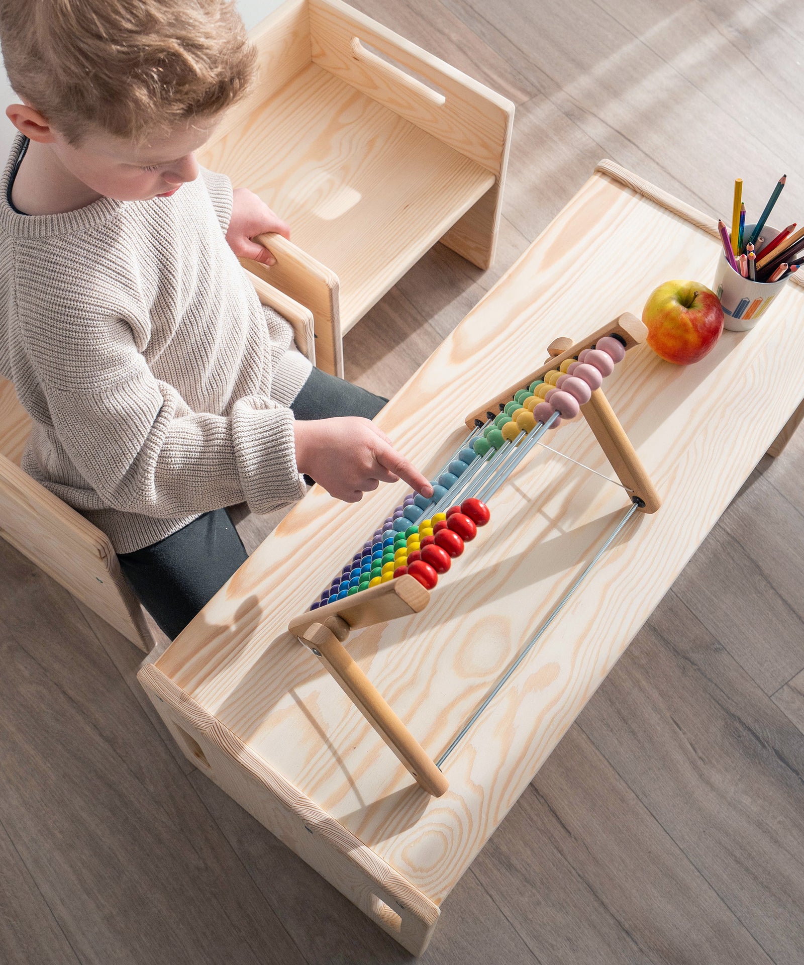 Kind spielt auf Bank Kiefer und nutzt sie als Tisch.