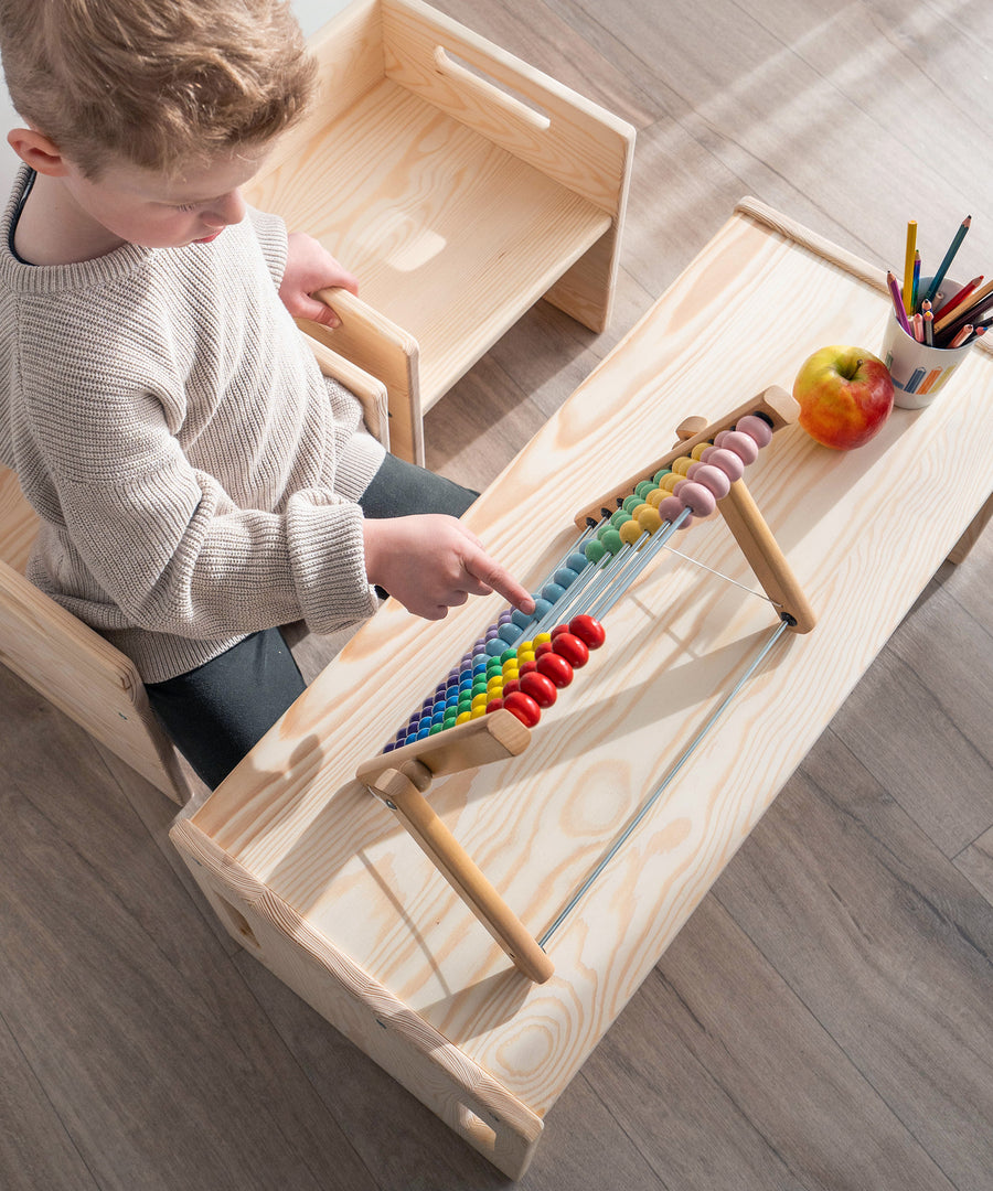 Kind spielt auf Bank Kiefer und nutzt sie als Tisch.