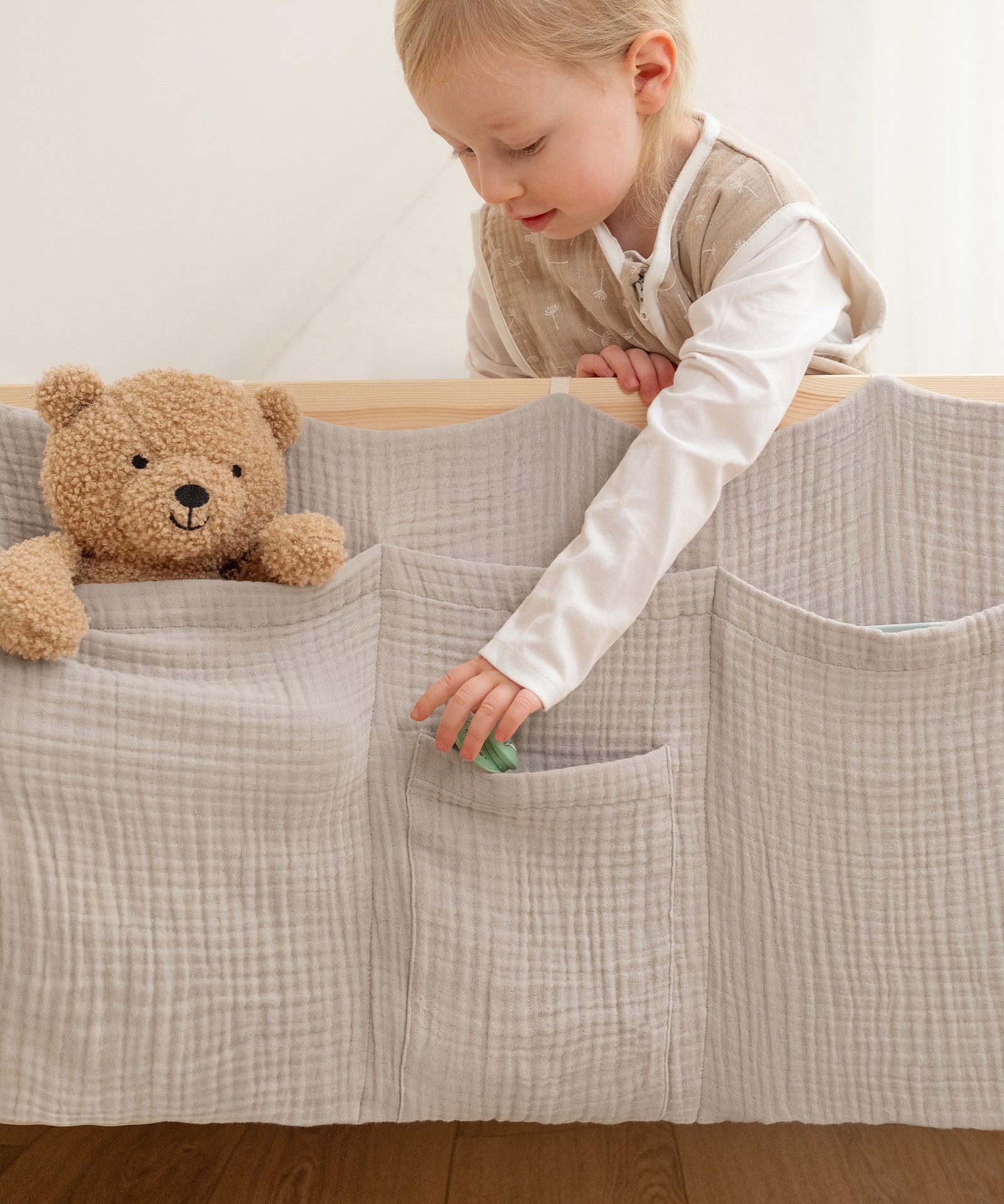 Geborgenheit in der Nacht*Nachts sind Kuscheltiere, Bücher oder Trinkflaschen griffbereit - für mehr Sicherheit und ein beruhigendes Gefühl im Dunkeln.|Kind verstaut einen Schnuller im Bett Organizer.