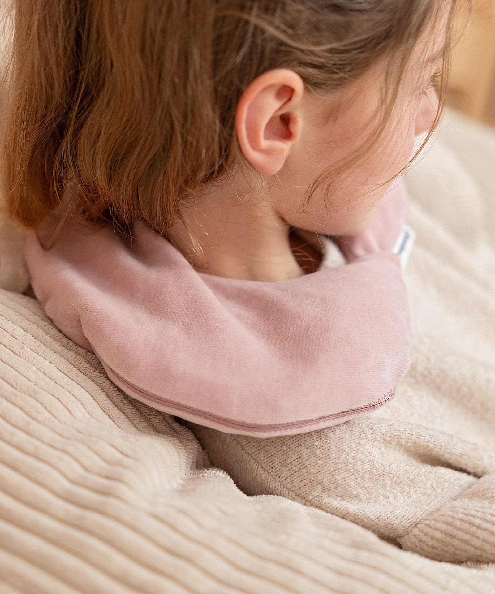 Weiches Mond-Wärmekissen aus Nicki-Stoff liegt sanft am Kindernacken.