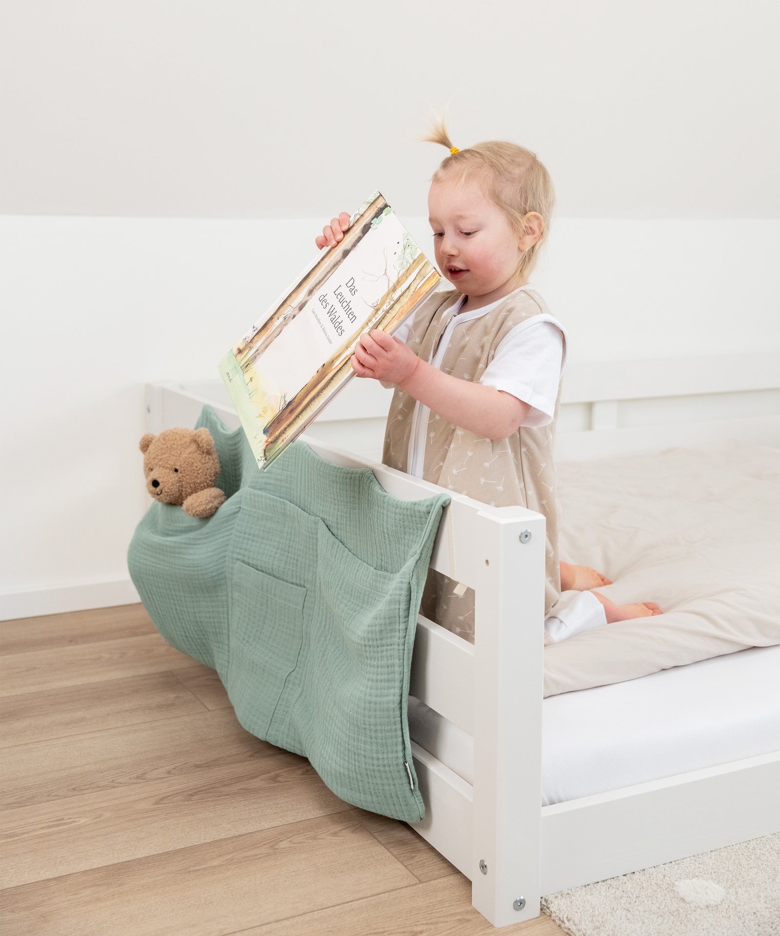 Kind verstaut Buch in Bett Organizer an Bodenbett.