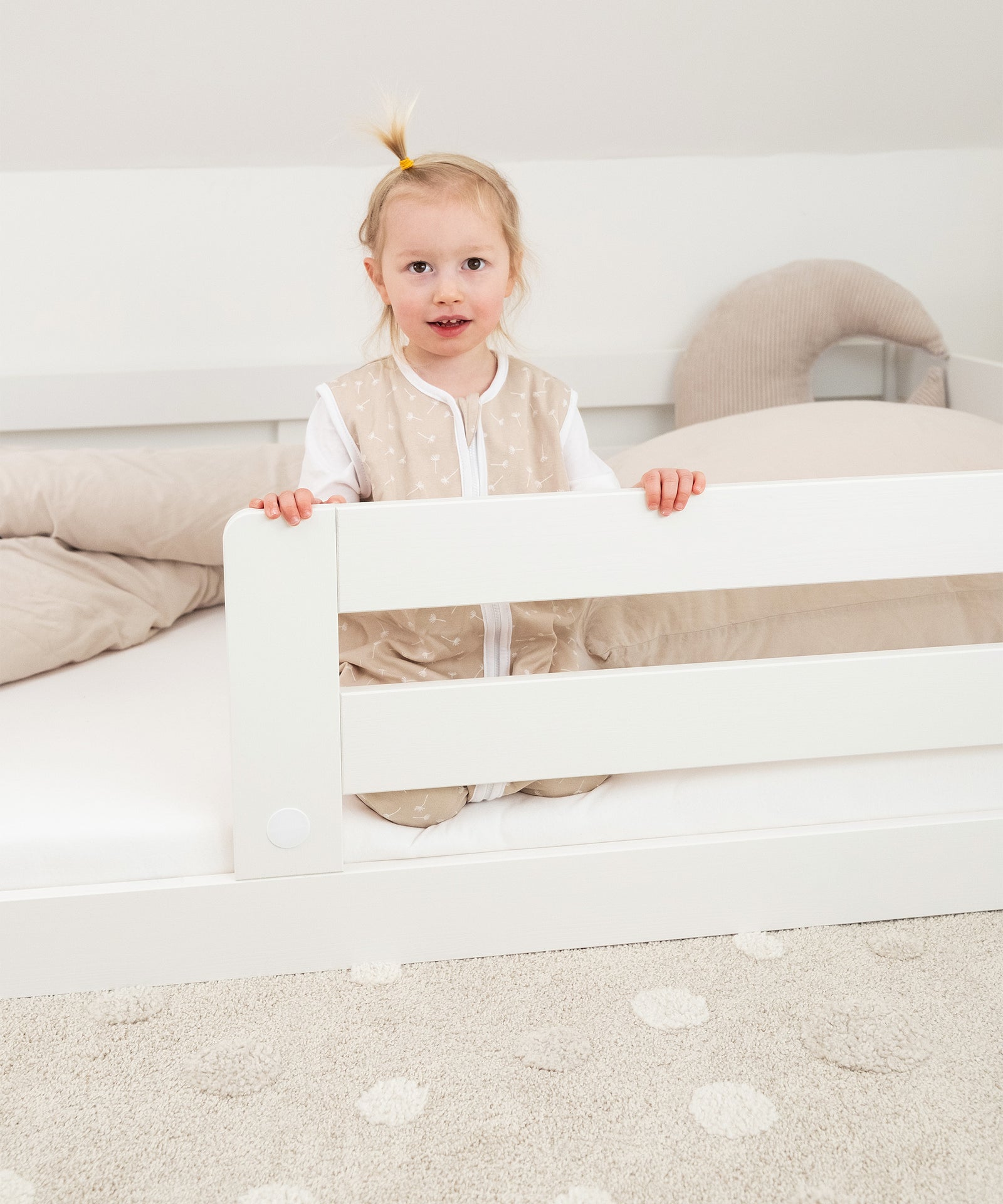 Sicher & geborgen*
Mit dem abnehmbaren Rausfallschutz bietet das Bett schon kleineren Kindern Sicherheit und sorgt für extra Geborgenheit.|Kind sitzt in Bodenbett Sona. 
