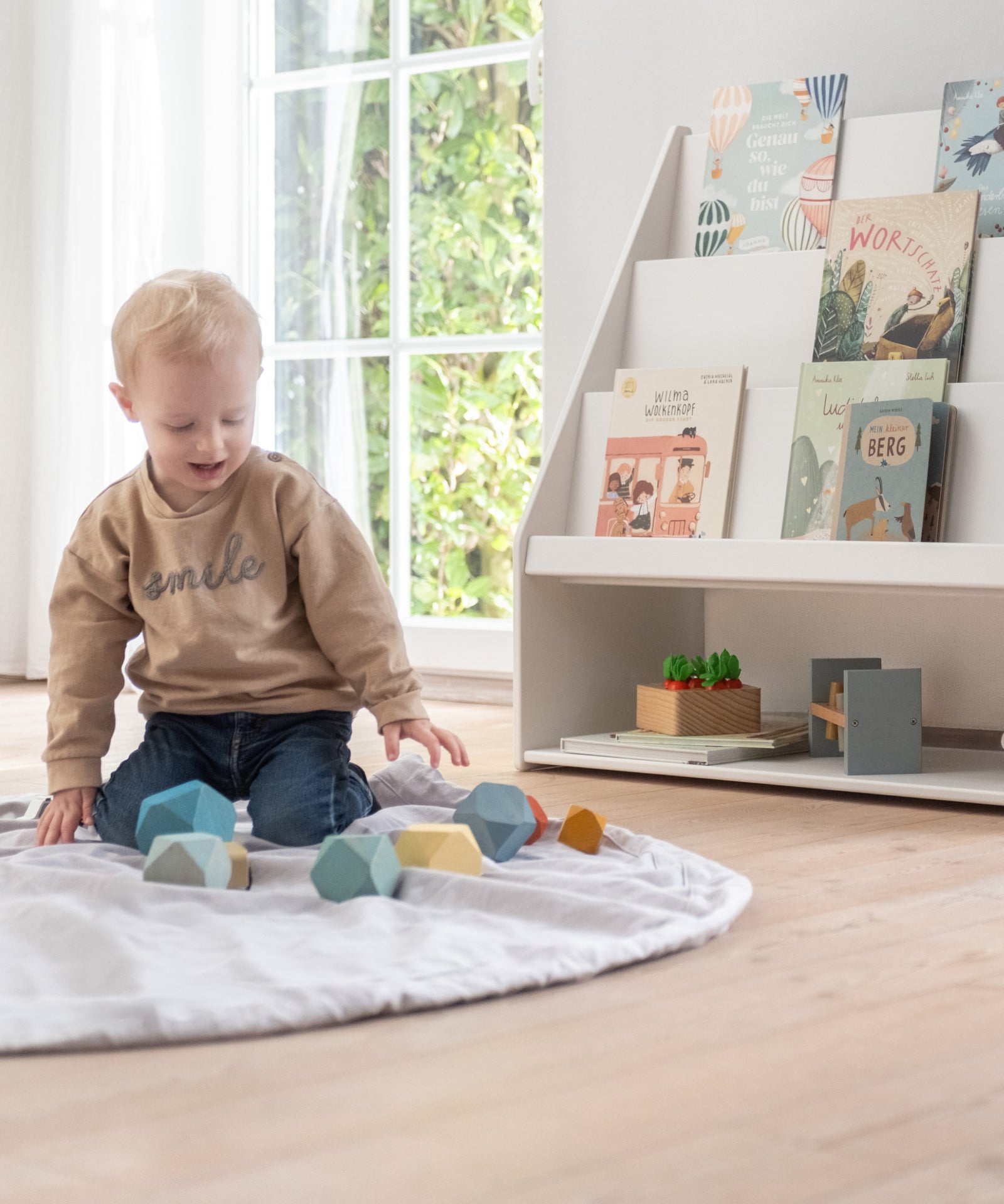 Kind spielt vor dem Bücherregal.