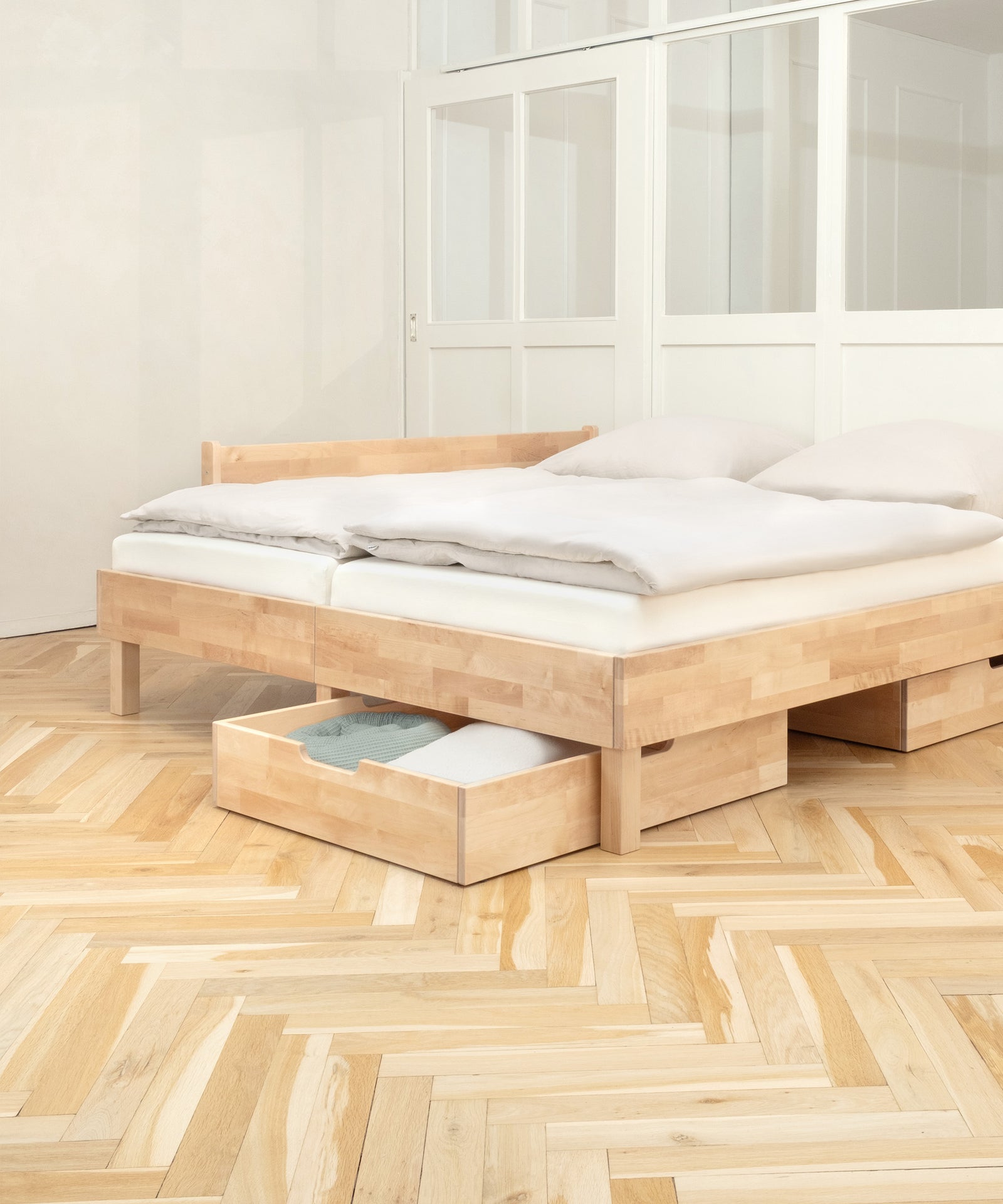 Die Doppelschublade und der Rausfallschutz sind praktisches Zubehör für das Doppelbett Plano in Birke.