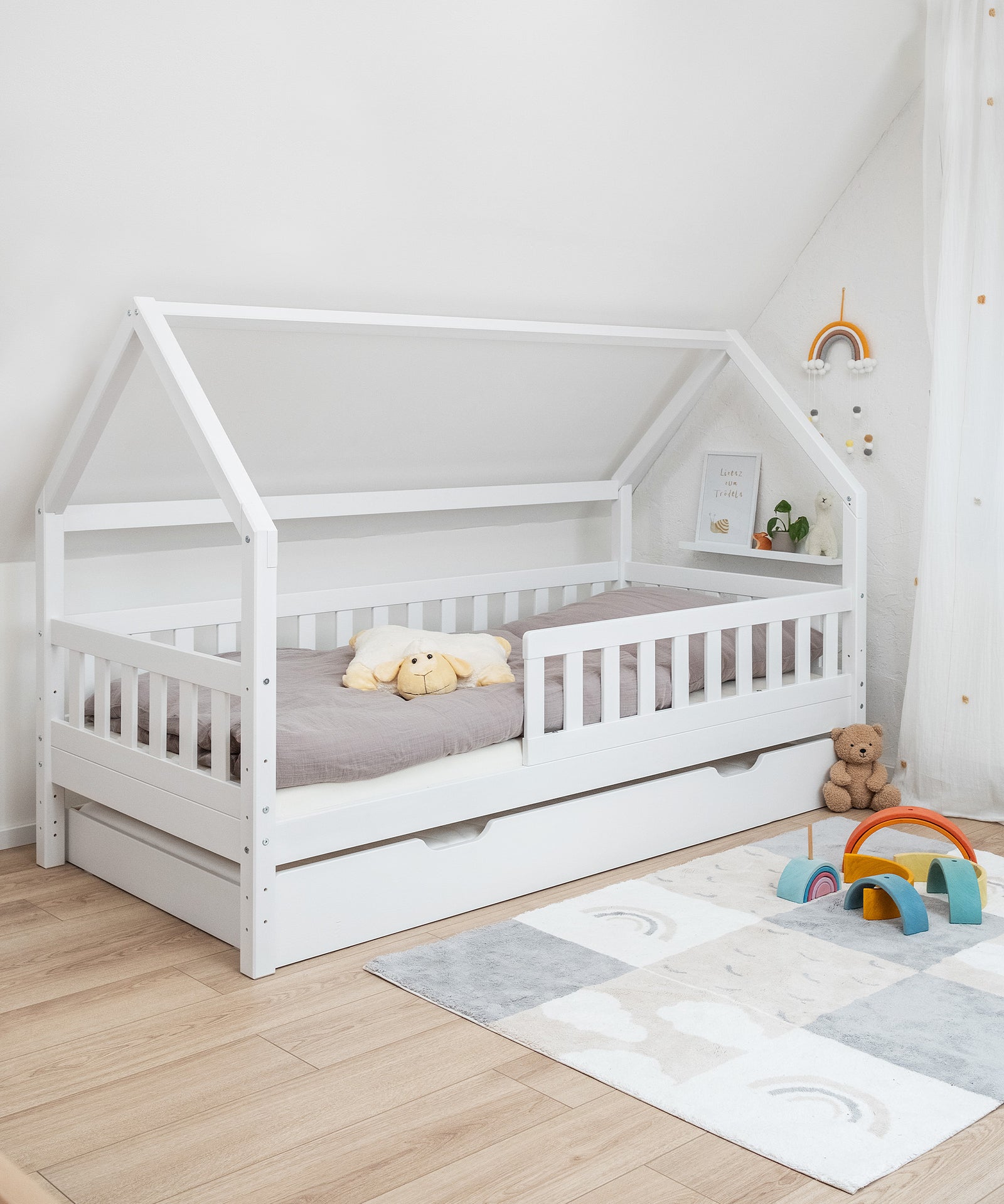 Zusätzlicher Schlafplatz*Unser optionaler Bettkasten bietet weitere Stauraumfläche oder einen extra Schlafplatz.|Hausbett Kiefer Weiß mit Bettkasten in Kinderzimmer.