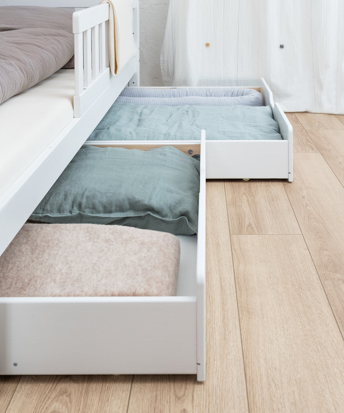 Doppelschublade vom Hausbett Kiefer in weiß befüllt und leicht ausgezogen, Schubladen haben praktische Rollen.