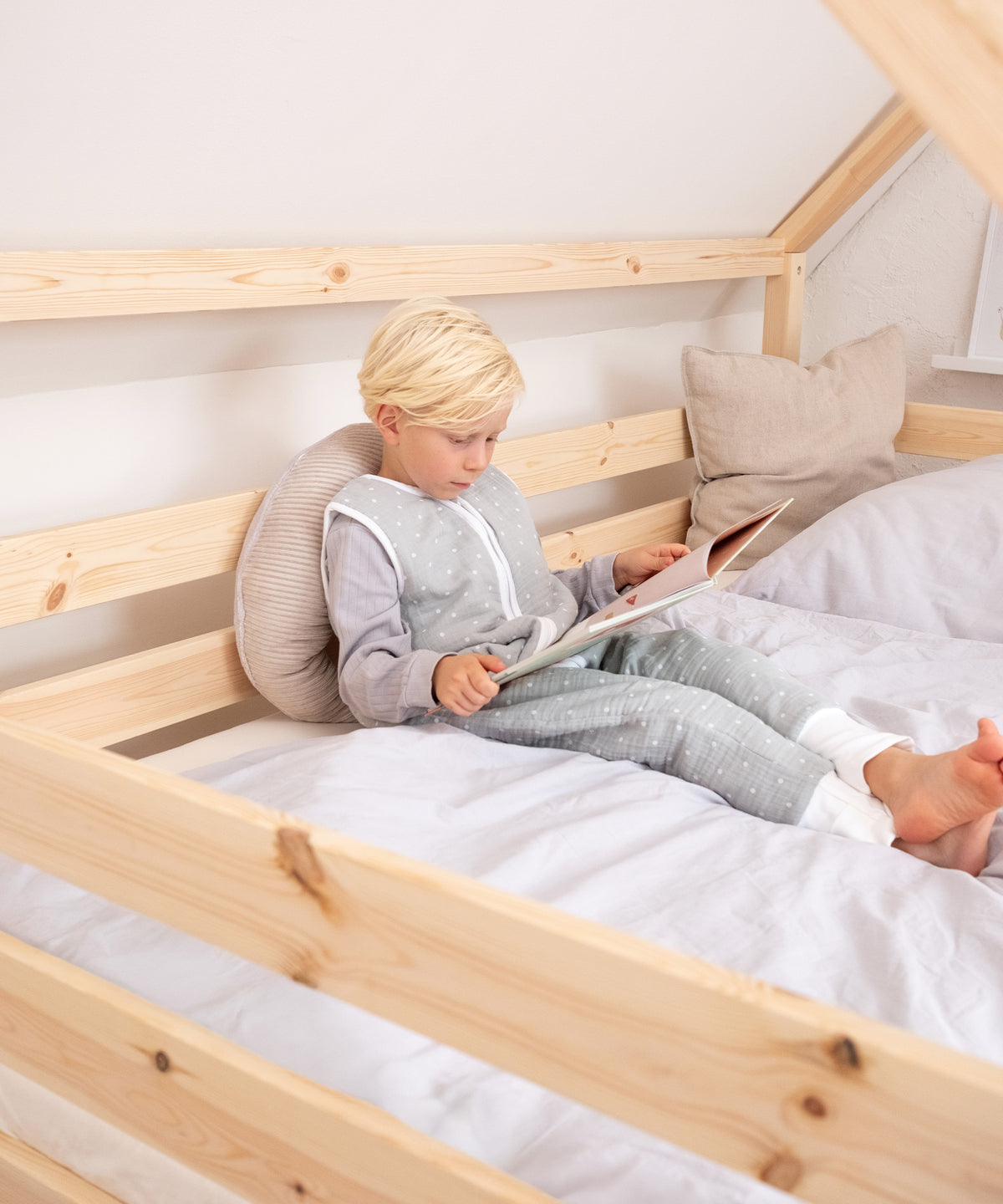 Kind sitzt in dem Hausbett und liest ein Buch.