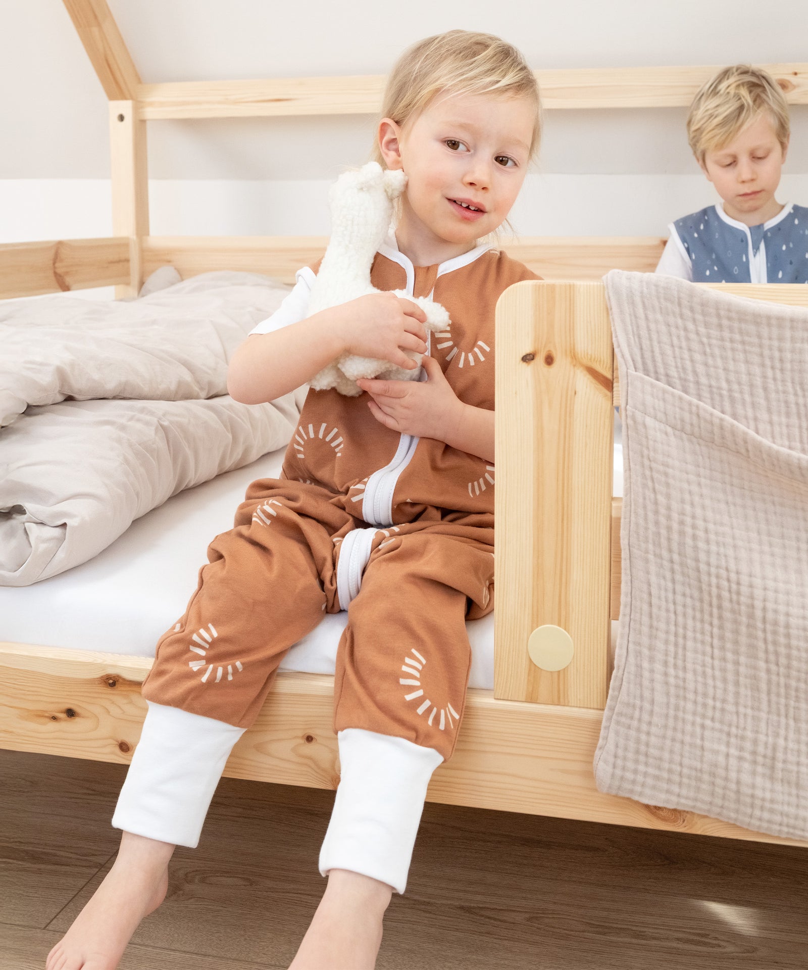 Zwei Kinder sitzen auf dem Hausbett Sona Natur.
