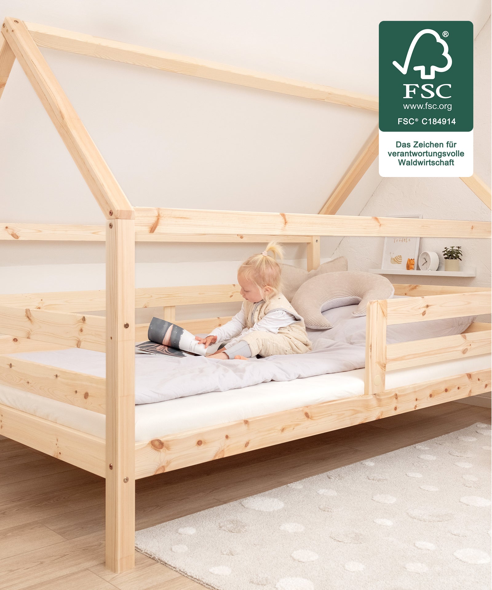 2 Farben & 2 Größen*Das Bett ist in Natur und Weiß in den Größen 90 x 200 cm und 120 ×200 cm erhältlich - genug Platz zum gemeinsamen Kuscheln!|In dem Hausbett sitzt ein Kind.