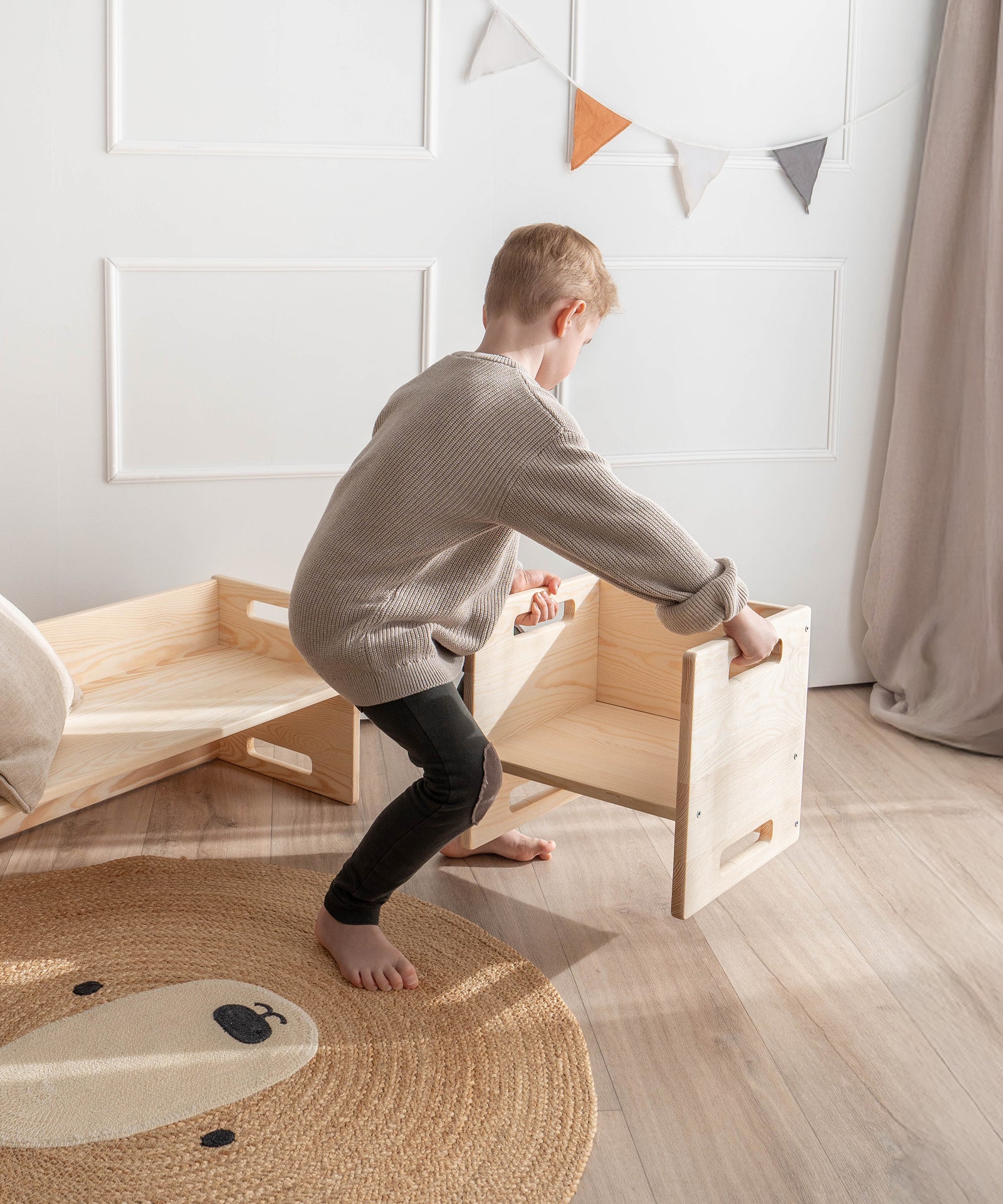 Kinderleicht & vielseitig*Aus Bank mach Tisch: Die praktischen Griffe ermöglichen es dir und deinem Kind, die Möbel ganz einfach zu greifen und zu wenden.|Kind trägt Hocker an Griffen im Kinderzimmer.