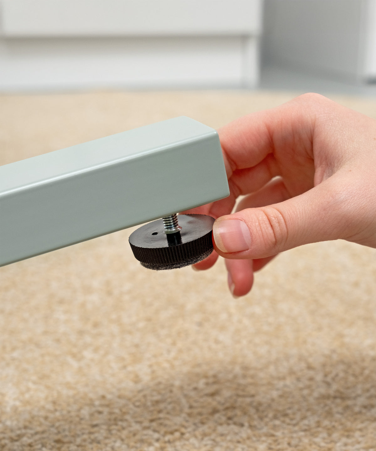 Bodenausgleichsschraube unter einem höhenverstellbaren Schreibtisch für sicheren Stand.