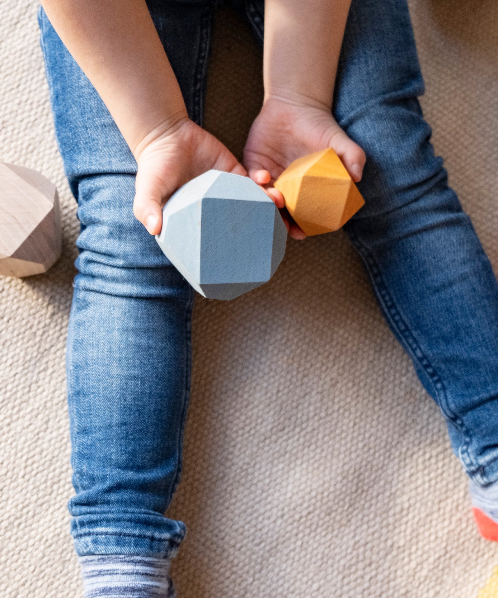 Kind hält zwei bunte Balance Holzbausteine in den Händen.