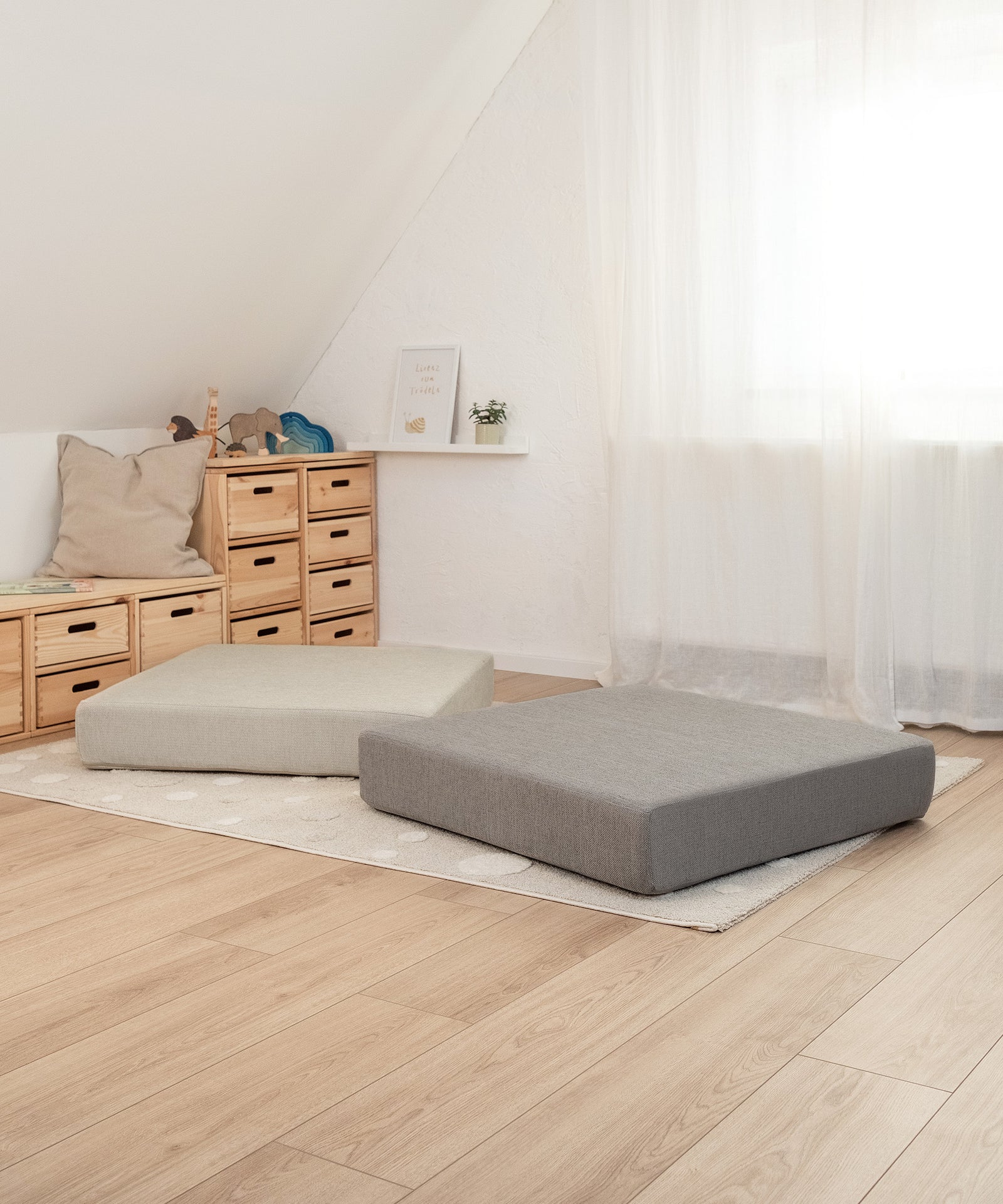 Quadratischer Hüpfspaß*Das 80 × 80 × 15 cm große Kissen eignet sich für Kinder ab ca. 12 Monaten und kann bis 40 kg Körpergewicht verwendet werden.| Hüpfpolster in Petrol und Natur liegen im Kinderzimmer.