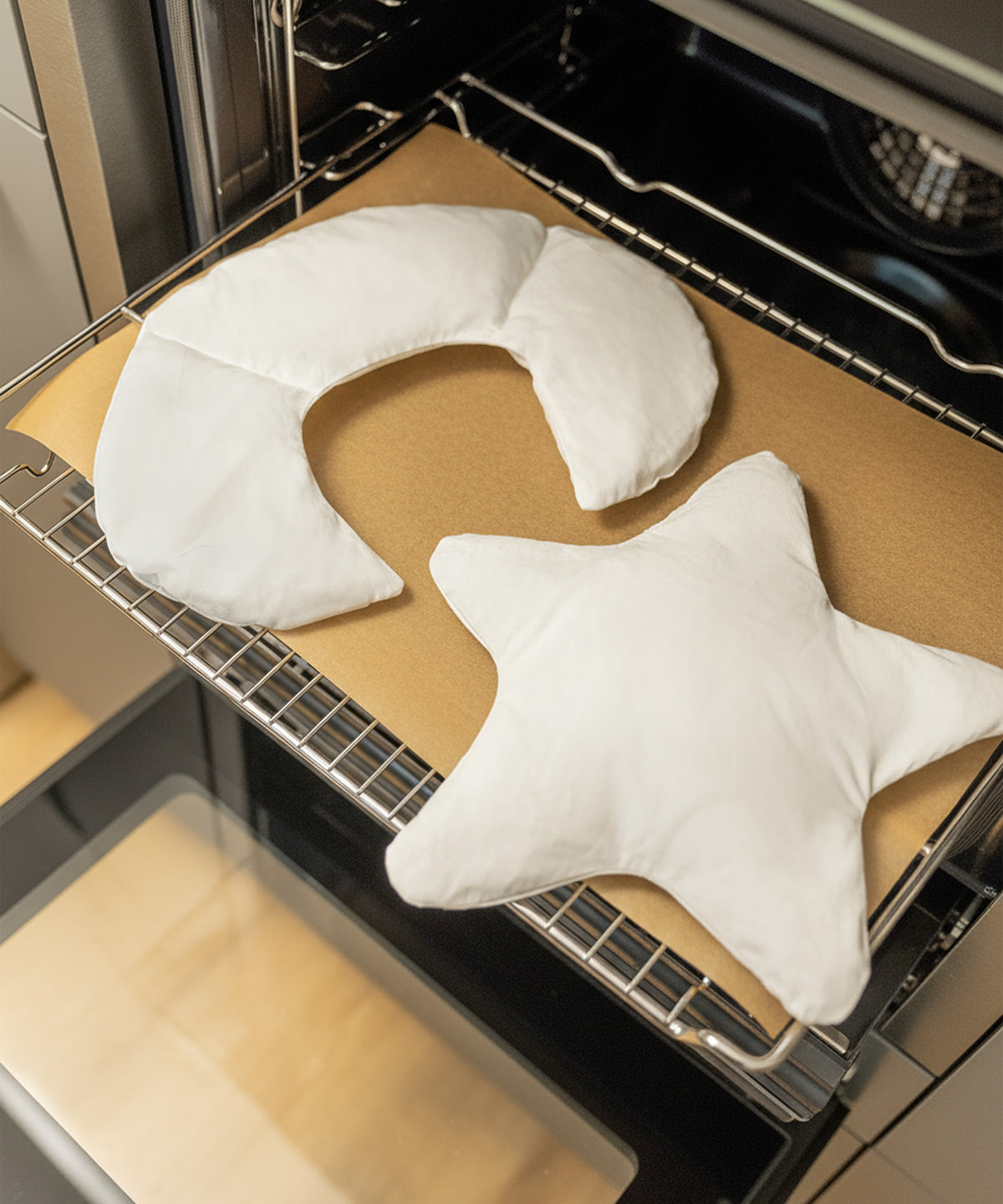 Herausnehmbares Inlett*Zum Erwärmen oder Kühlen nur das wiederverwendbare Inlett mit Kirschkernfüllung nutzen - hygienisch und langlebig.| Das Inlett des Kirschkernkissens liegt auf einem Backblech mit Backpapier, um im Ofen erwärmt zu werden.