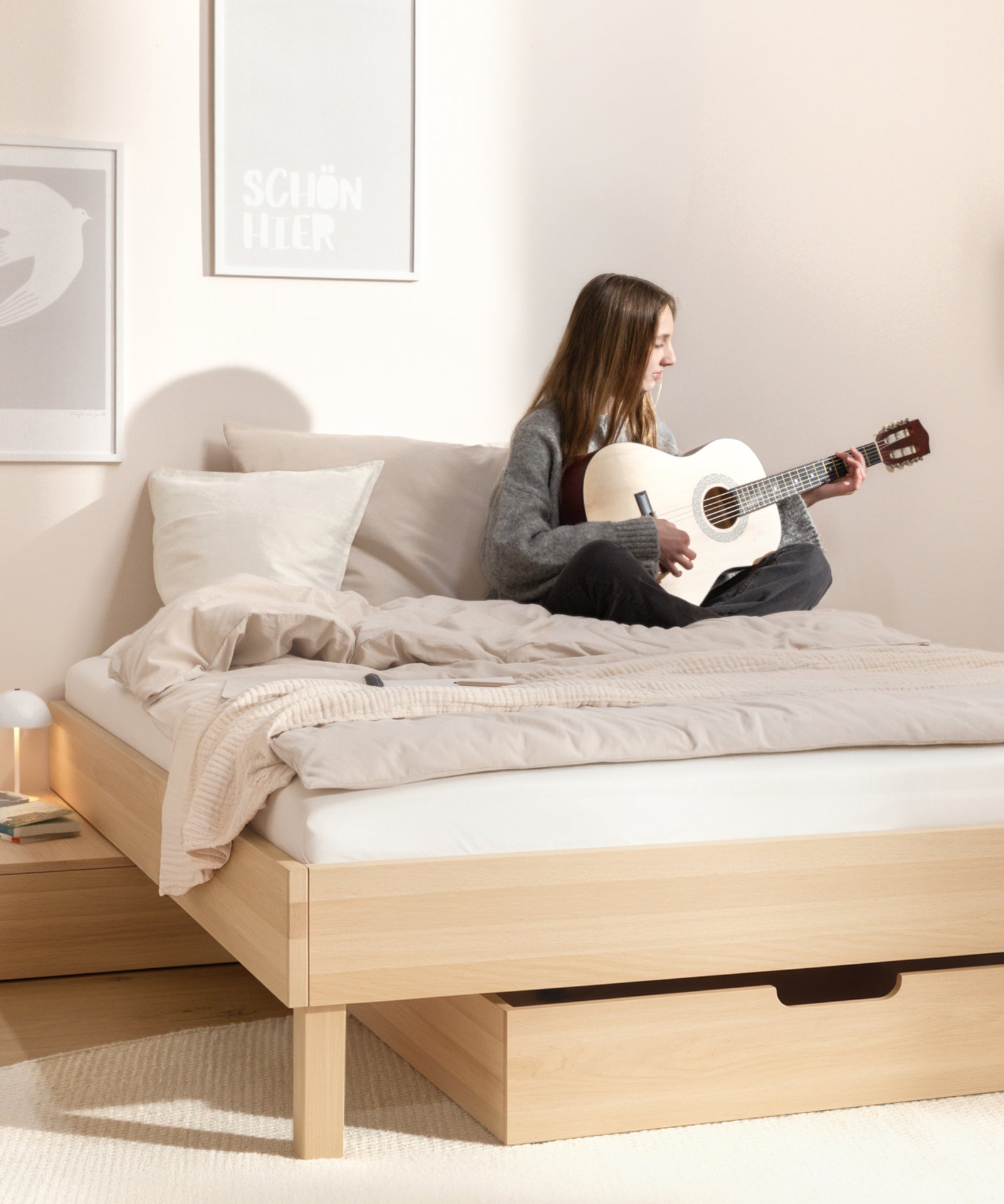 Mädchen sitzt auf dem Jugendbett und spielt Gitarre.