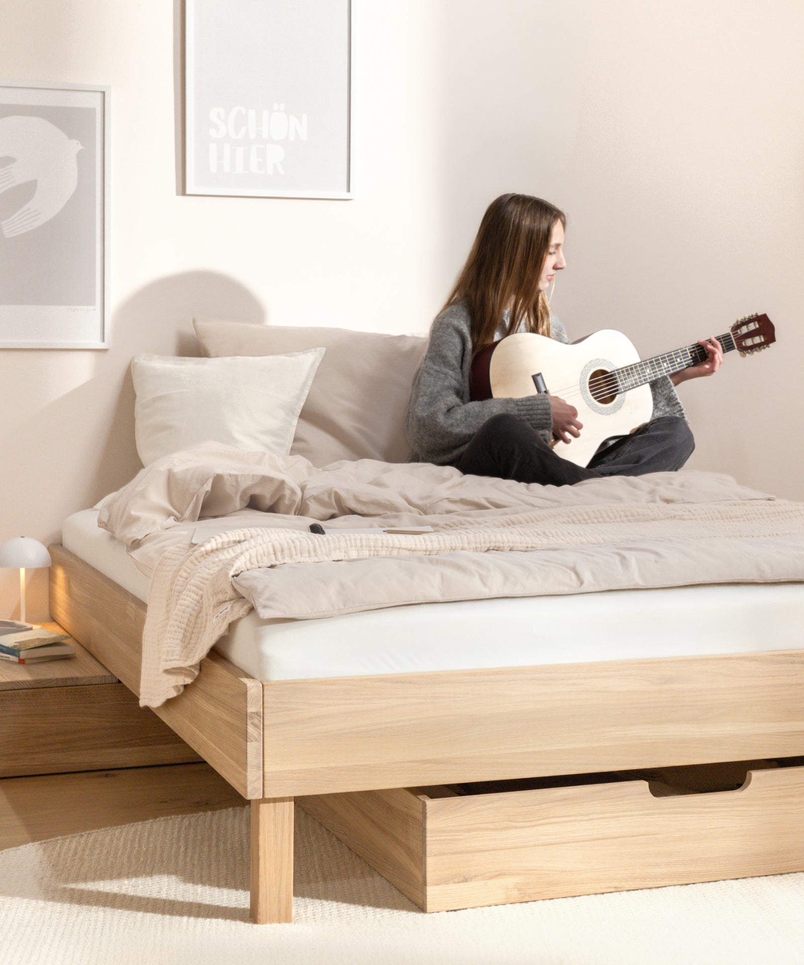Mädchen sitzt auf dem Jugendbett und spielt Gitarre.
