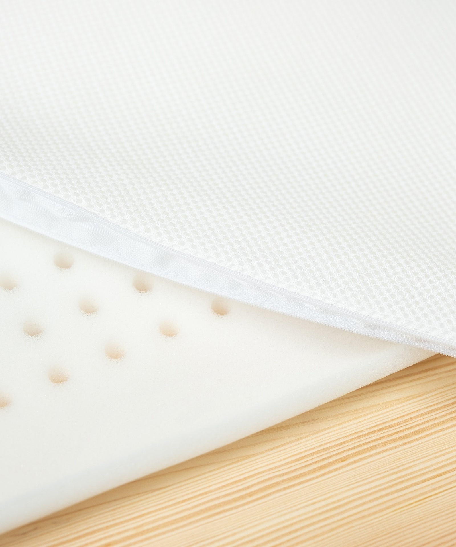 Pflegeleicht & praktisch*Der Meshbezug aus 100% Polyester lässt sich einfach abnehmen und bei 30°C waschen - bestens geeignet für den Alltag mit Baby.|Nahaufnahme Schaumstoff mit Löchern für Belüftung und Mesh-Bezug.