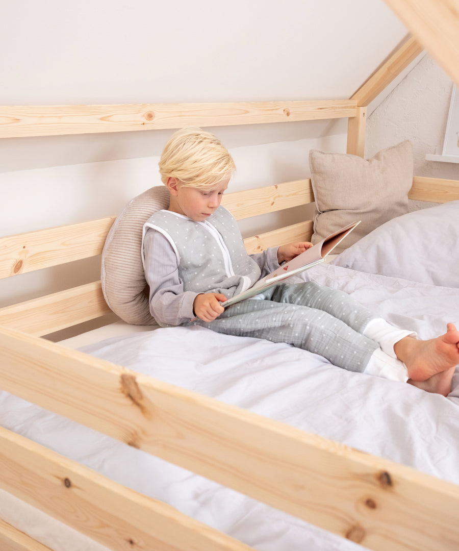 Kind liest entspannt im gemütlichen Hausbett aus Kiefernholz