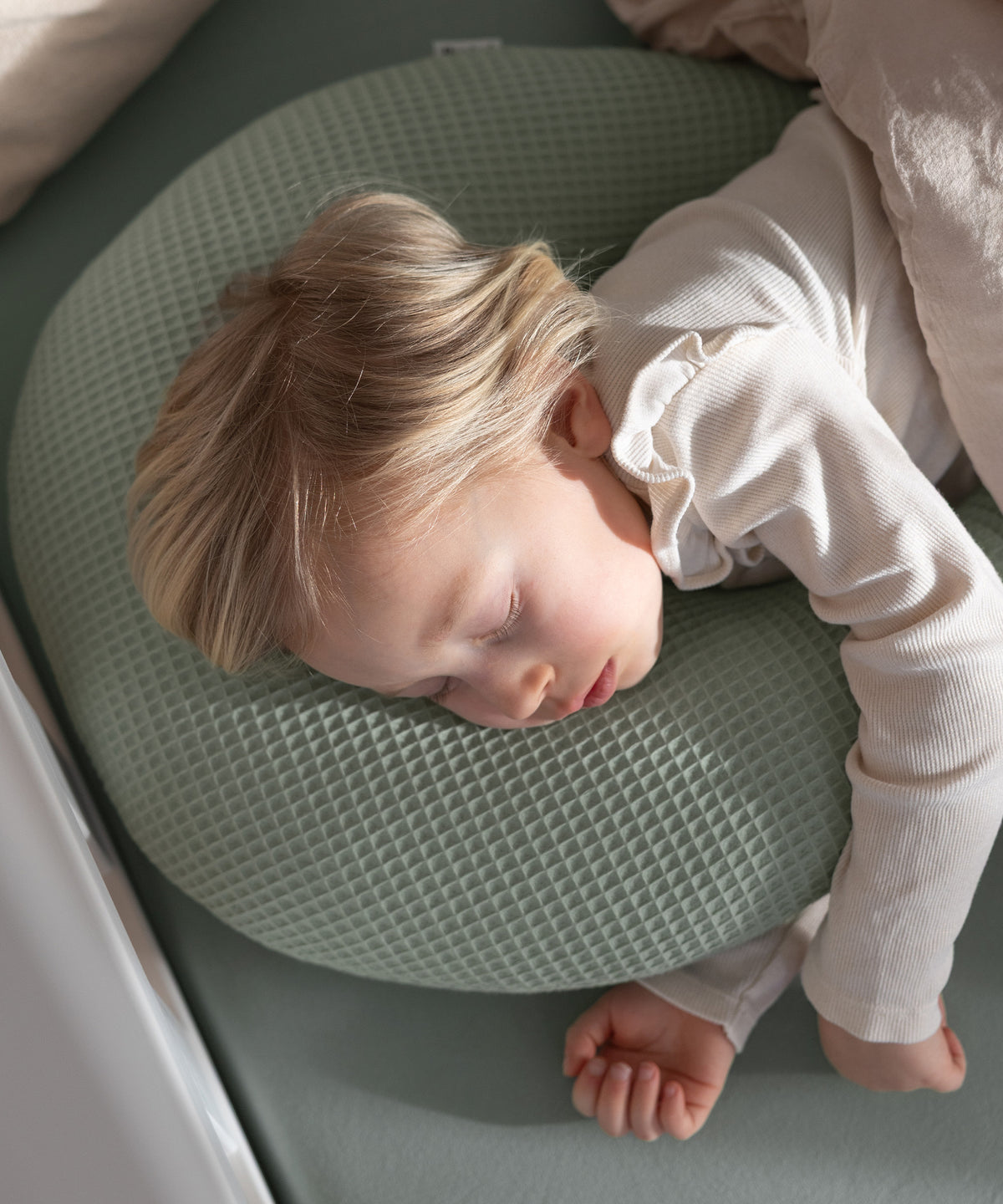 Kind schläft auf dem Kuschelkissen.