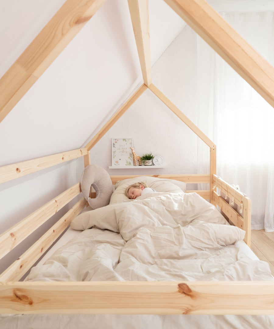 Kind schläft geborgen im Hausbett aus Kiefernholz