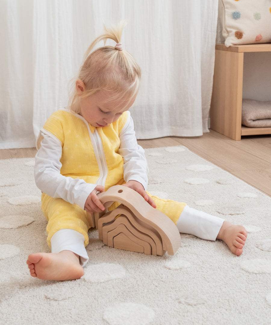 Kind in Schlafsack mit Beinen beim Spielen am Kinderzimmerboden.