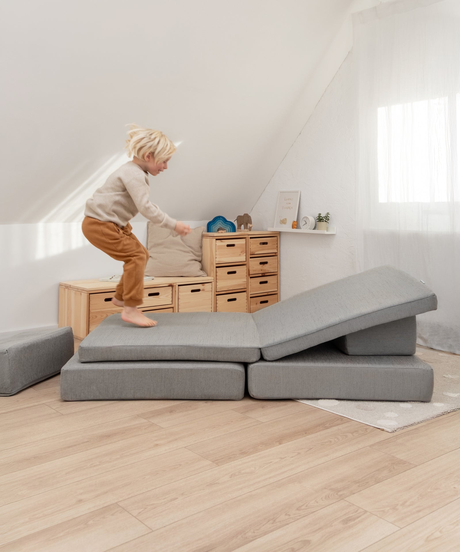 Kind bewegt sich spielerisch auf dem Spielsofa.