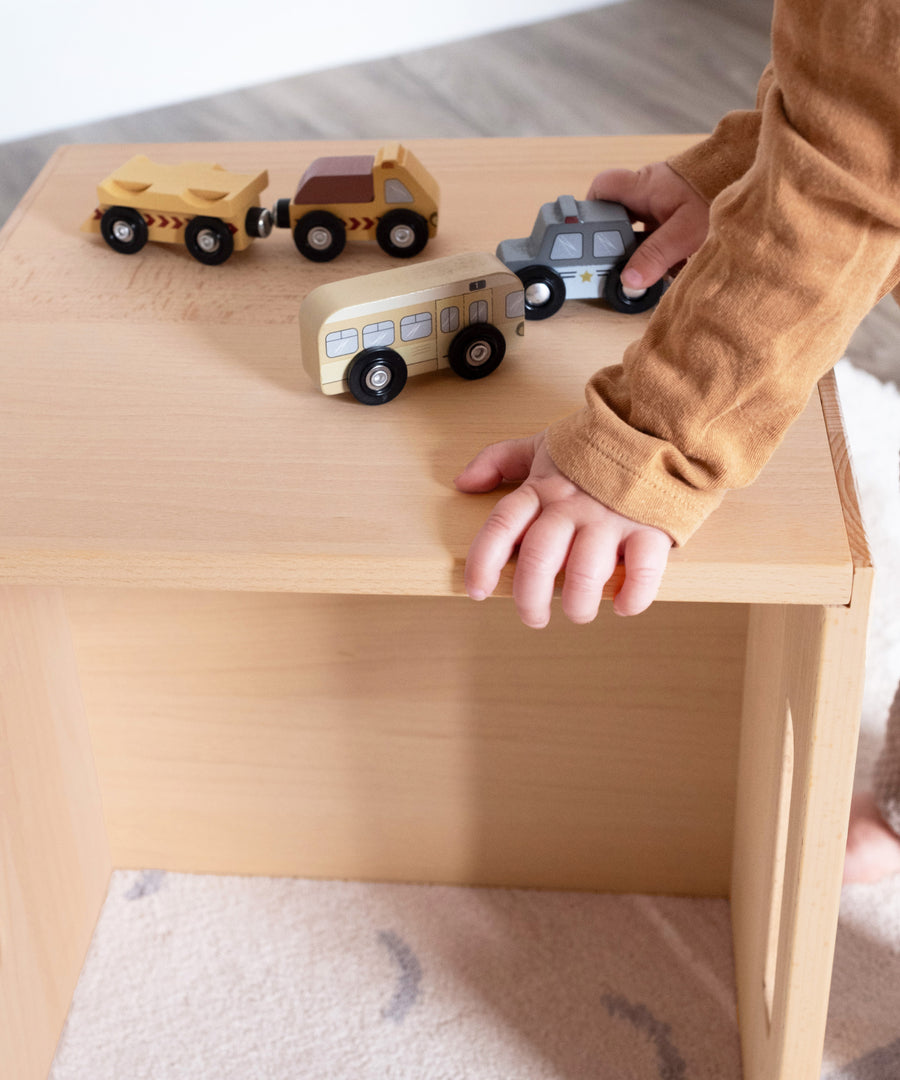 Kind spielt auf Hocker aus Buchenholz im Kinderzimmer.