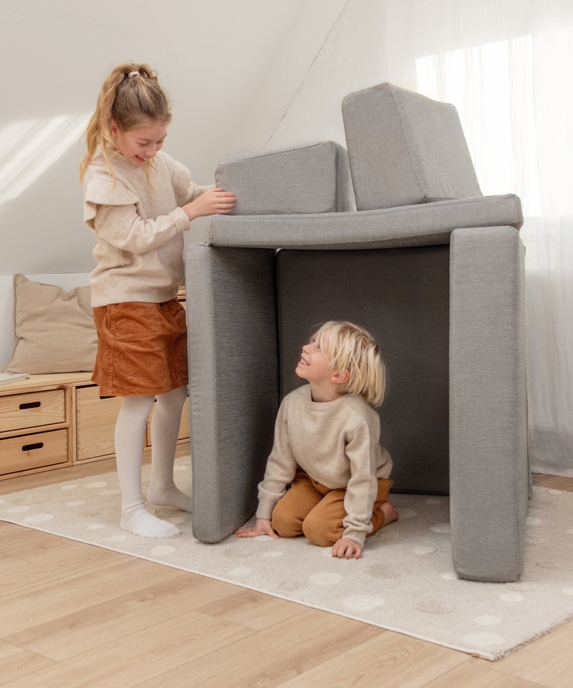 Kinder bauen eine Höhle aus dem modularen Spielsofa.