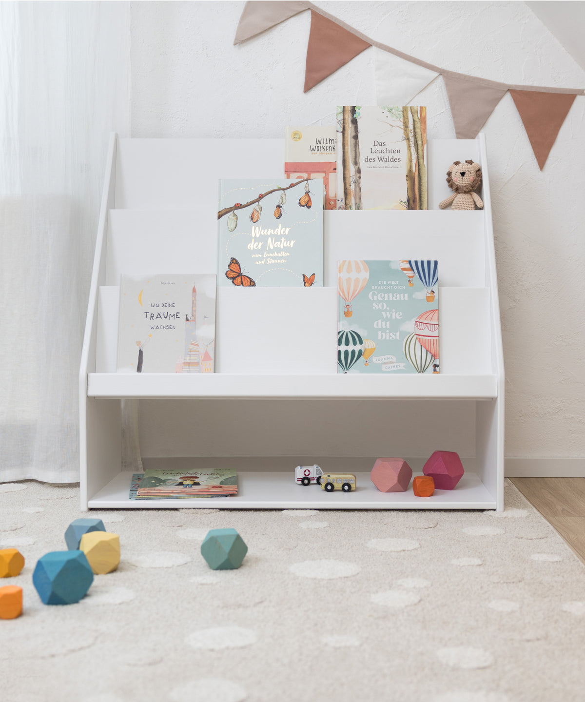 Bücher & Spielzeug an einem Ort*Lieblingsbücher und Spielzeug finden hier gemeinsam ihren Platz - nah am Kind und genau dort, wo gespielt und gelesen wird.|Weiß lackiertes Kinderbücherregal aus Kiefernholz mit frontaler Buchpräsentation.