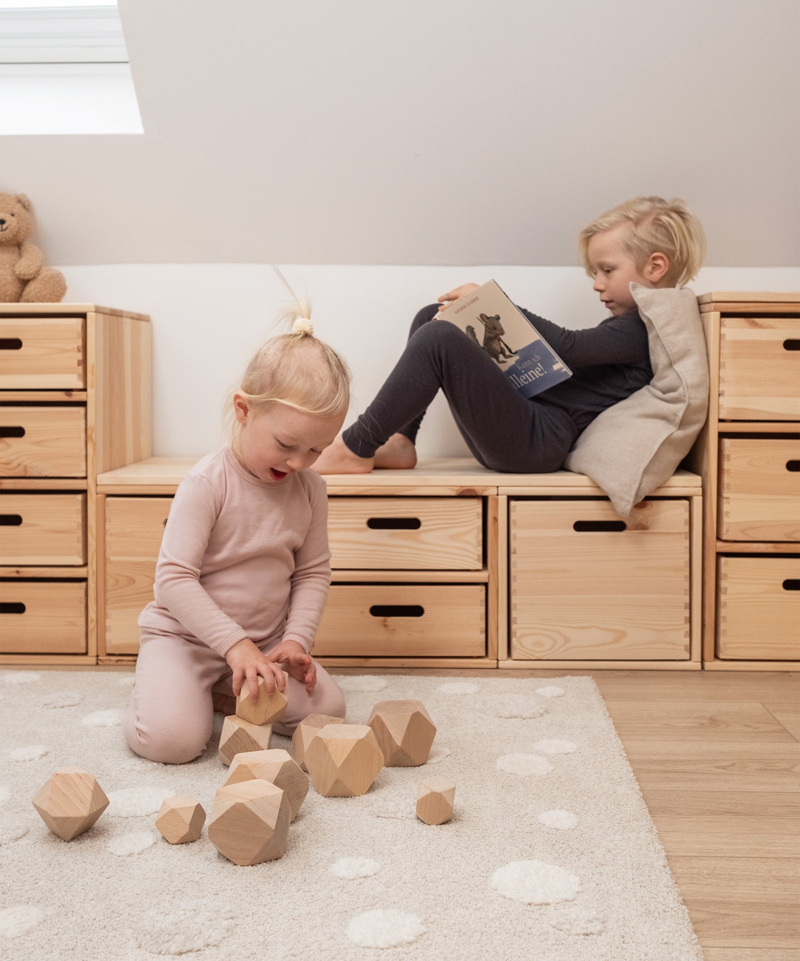 Kinder spielen in Merino Unterwäsche in Rosé und Anthrazit.