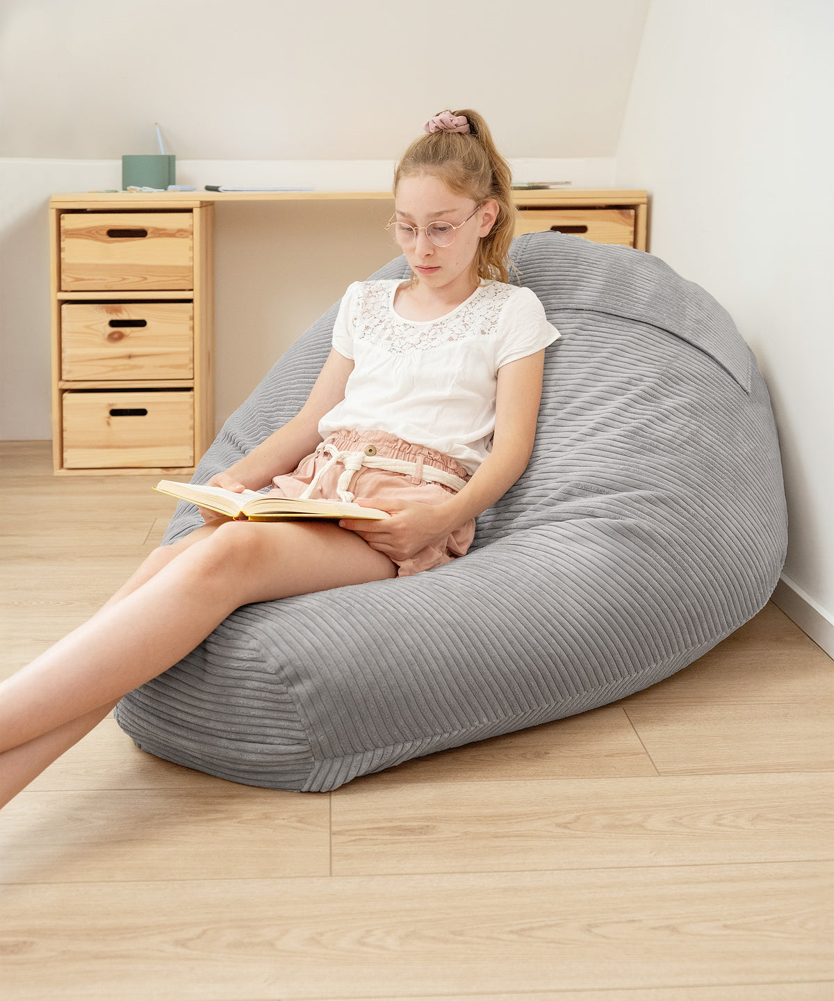 Kind sitzt auf Sitzsack und liest ein Buch.