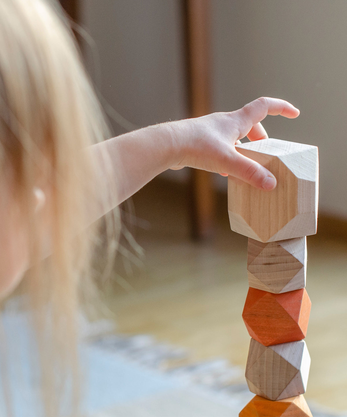 Mädchen stapelt Turm aus Balanciersteinen.