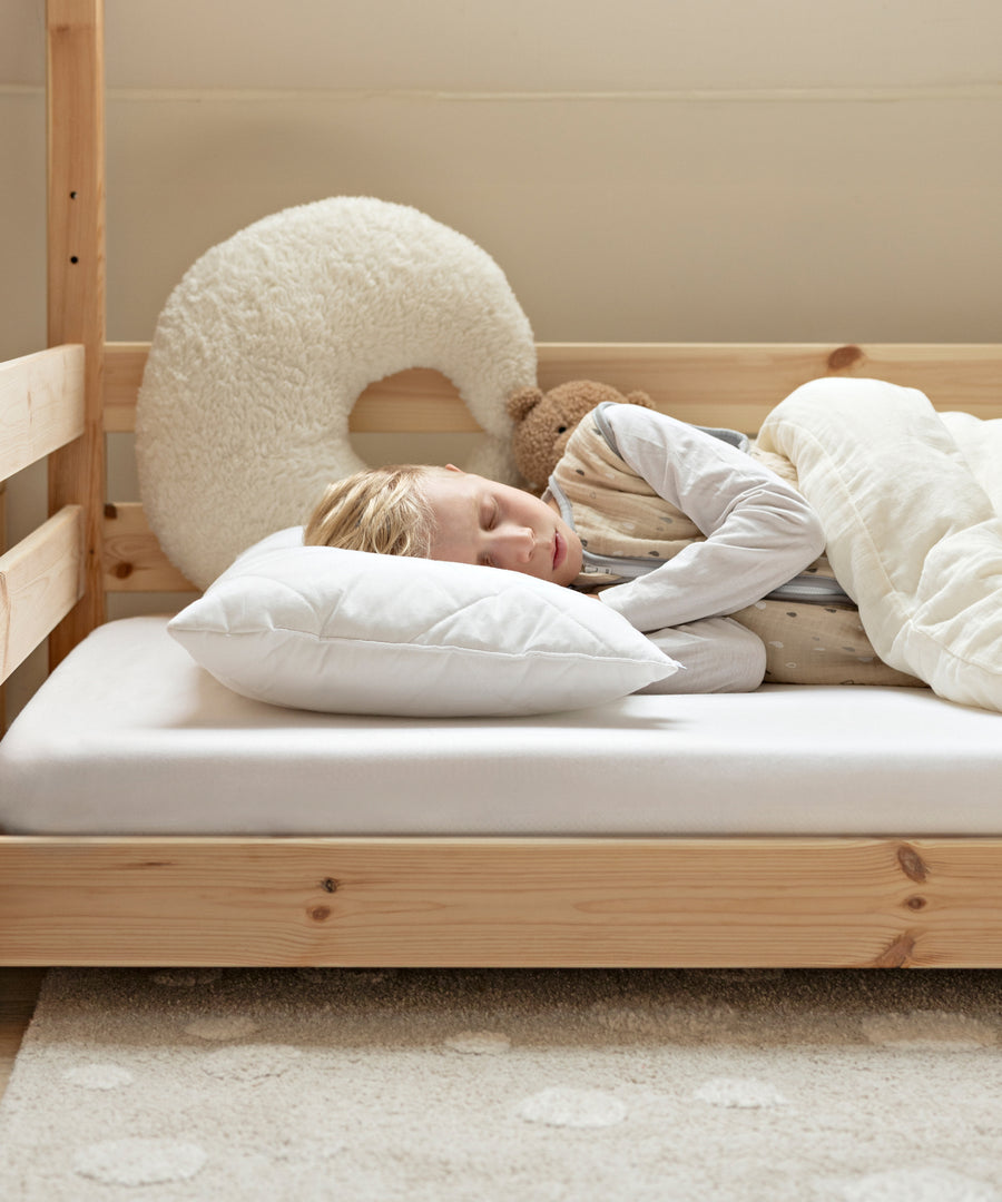 Kind schläft entspannt auf dem Kinderkissen.