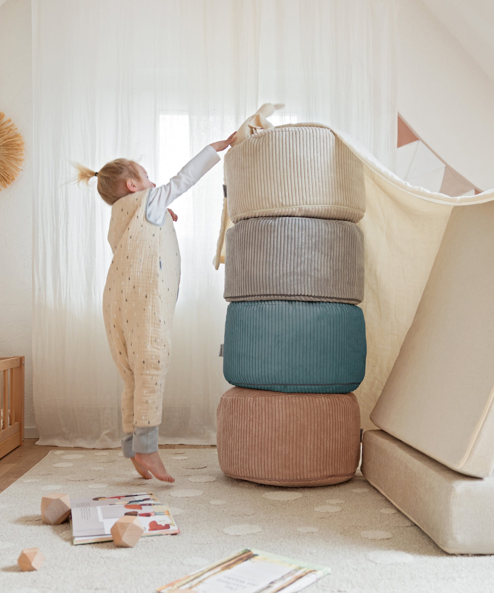 Vielseitig einsetzbar*Der Pouf ist leicht und lässt sich schnell in unterschiedlichen Situationen im Kinderzimmer oder in der Leseecke nutzen.|Kind baut einen Turm aus den Poufs